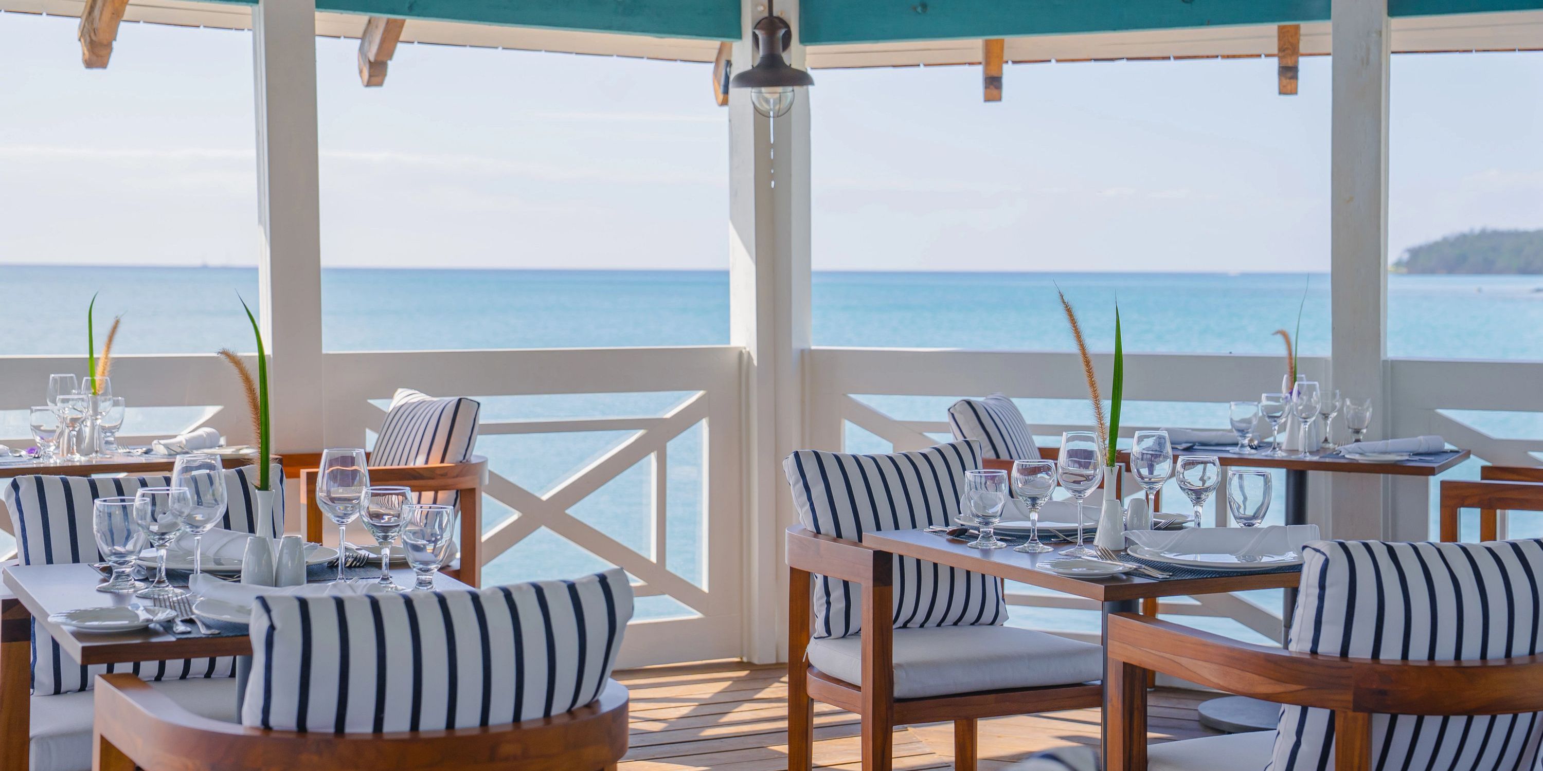 Secrets St Lucia: Outdoor seaside dining set for a destination wedding, striped cushions, ocean view.