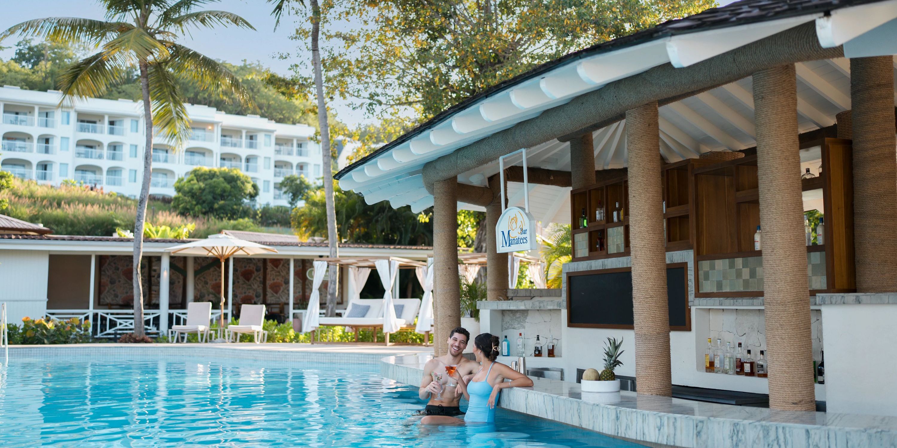 A couple celebrates their destination wedding with drinks at the swim-up pool bar at Secrets St Lucia resort.