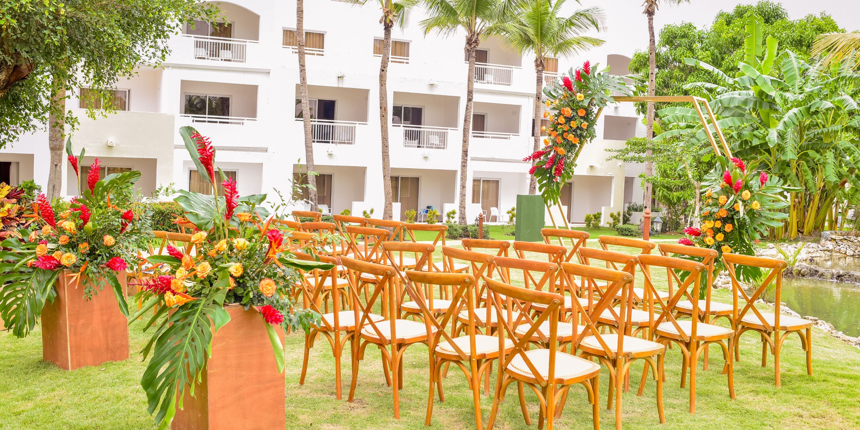 Destination wedding ceremony at Sunscape Dominicus La Romana with wooden chairs and colorful flowers.