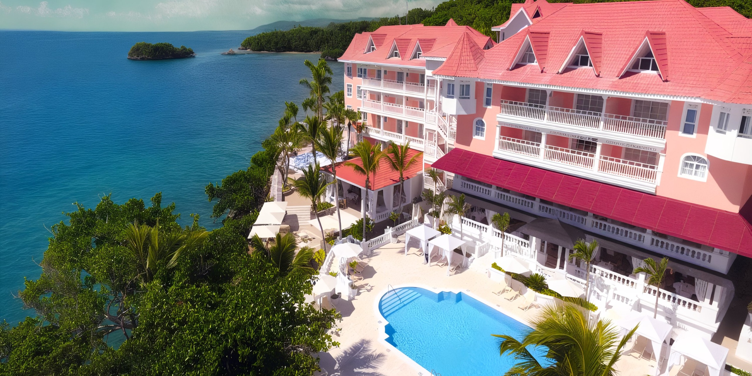Aerial view of Bahia Principe Grand Samana, featuring pink-roofed buildings, palm trees, a swimming pool, and a scenic ocean backdrop.