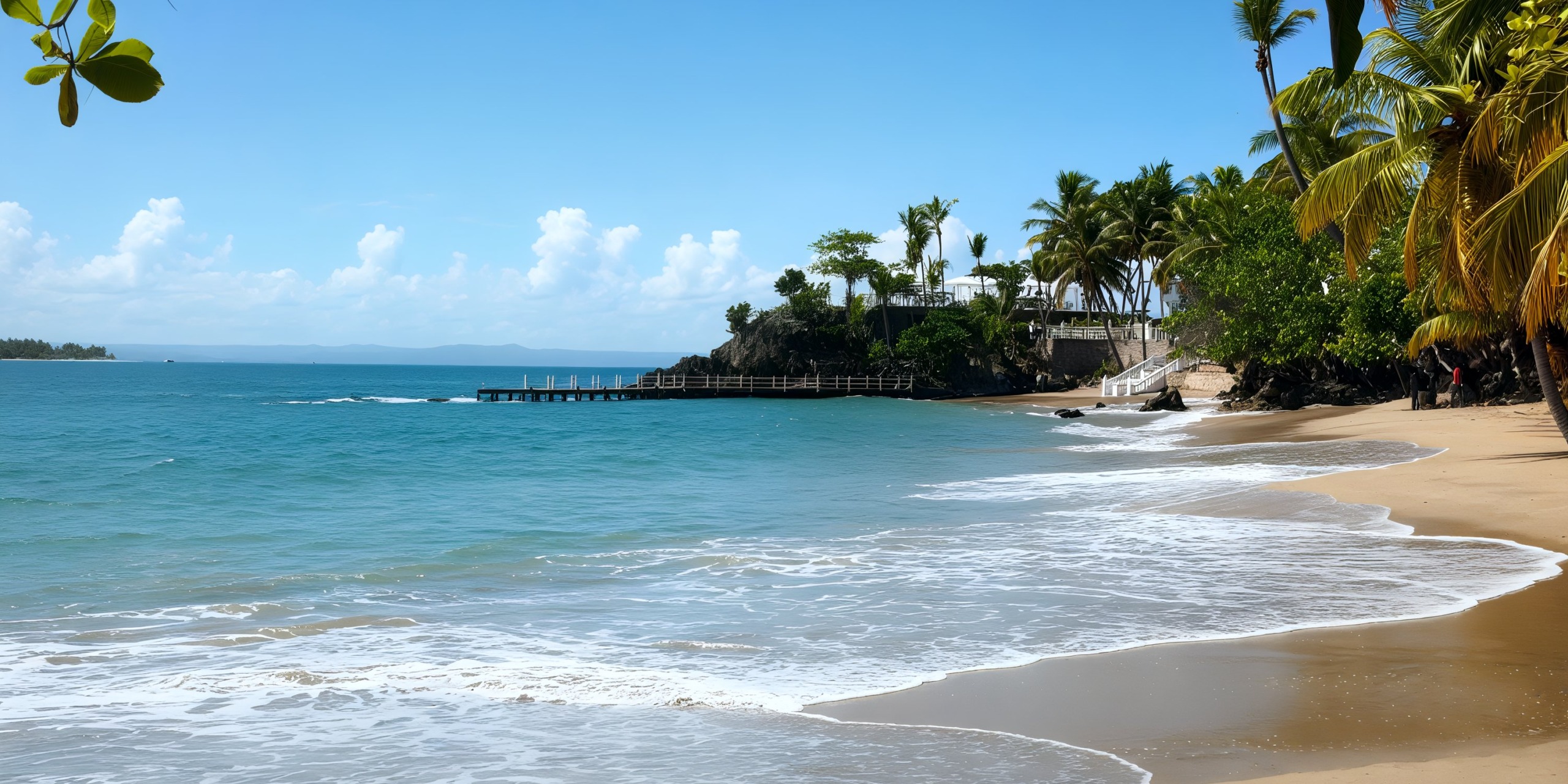 A tranquil view at the Bahia Principe Grand Samana with gentle waves lapping against the sandy shore, lush palm trees swaying, and a distant pier beneath a clear blue sky.