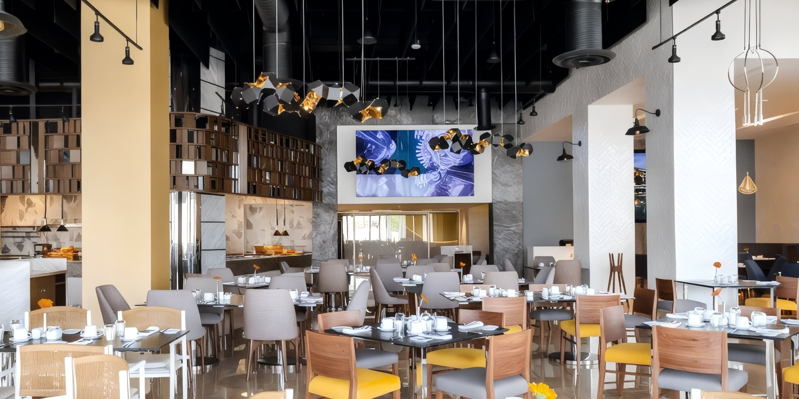 The Garza Blanca Cancun restaurant interior features neatly arranged tables and chairs, decorative lighting, and a large screen on the wall displaying graphics.