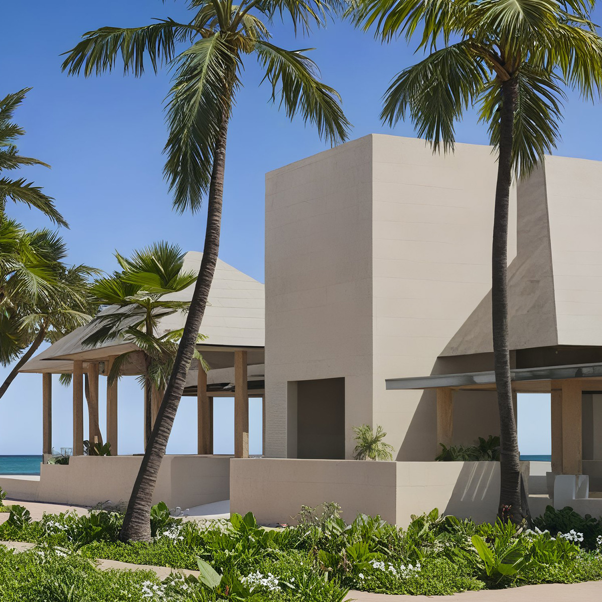 Modern beige building with flat roofs, surrounded by palm trees and lush greenery, set against a clear blue sky.