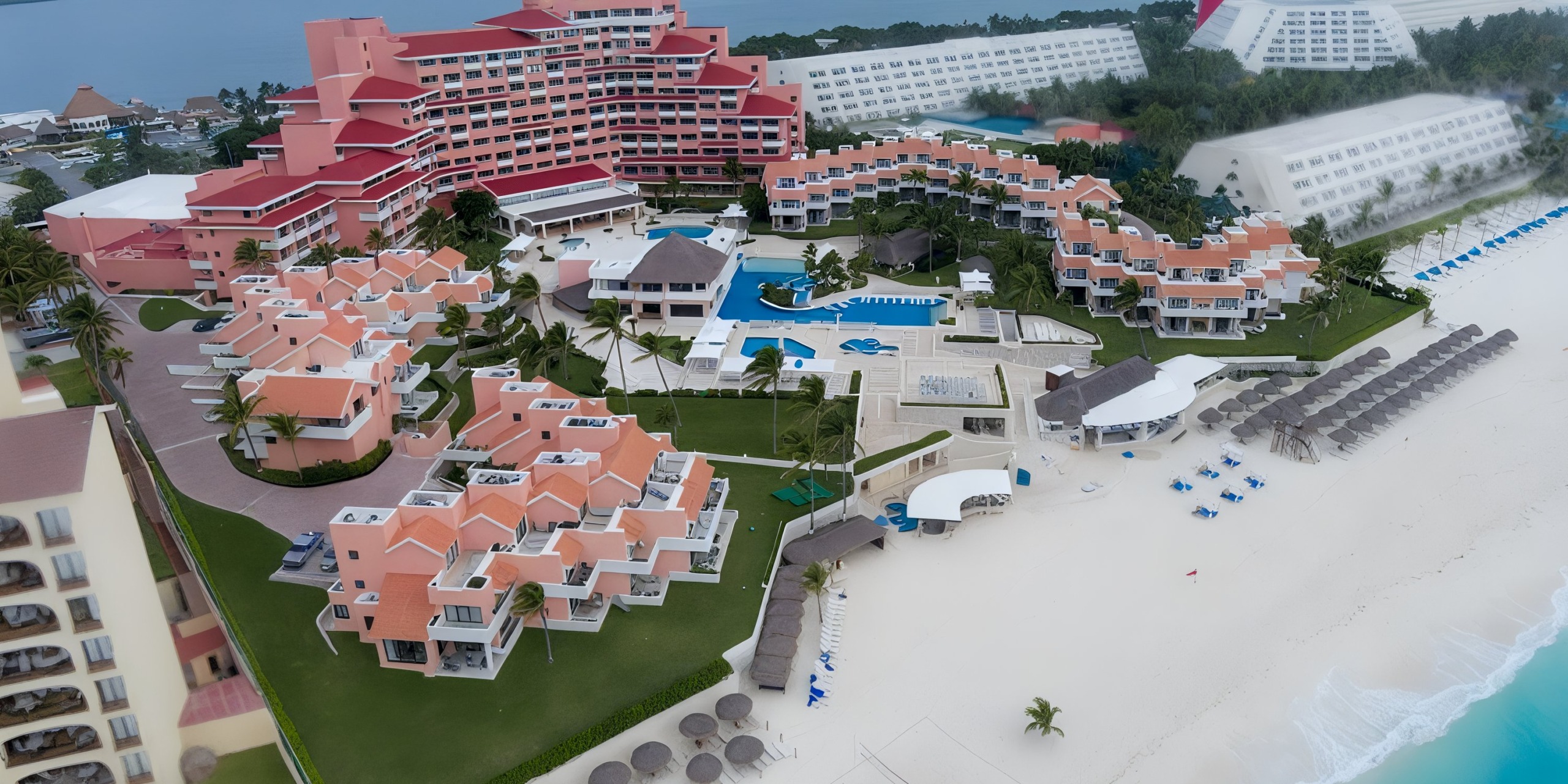 Aerial view of the Wyndham Grand Cancun, a beachfront resort featuring various buildings, pools, and sun loungers on a sandy beach.