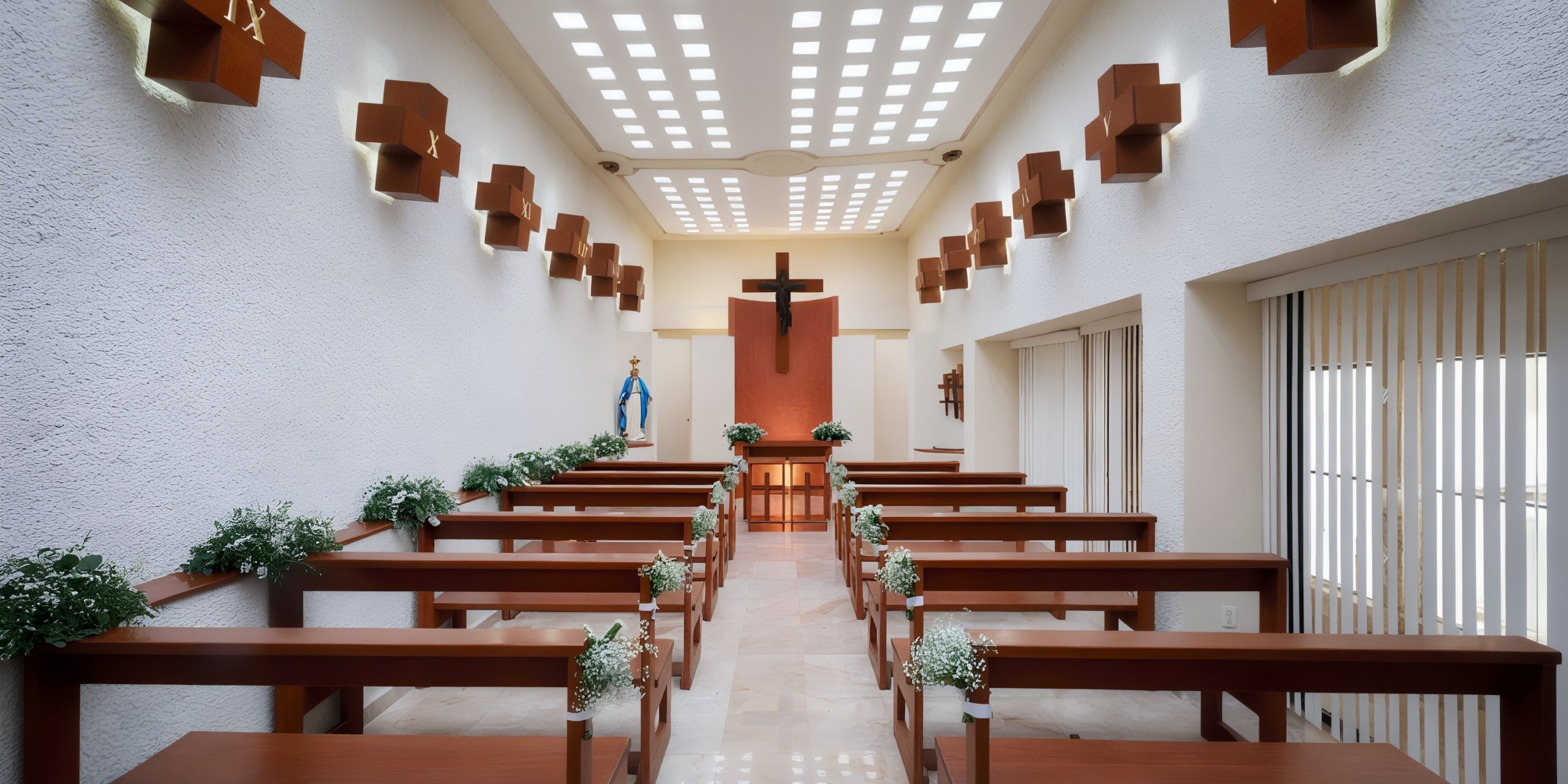 The interior of the Wyndham Grand Cancun features a modern, minimalist chapel design with wooden benches, a central aisle, a large cross adorning the front wall, and ceiling lights.