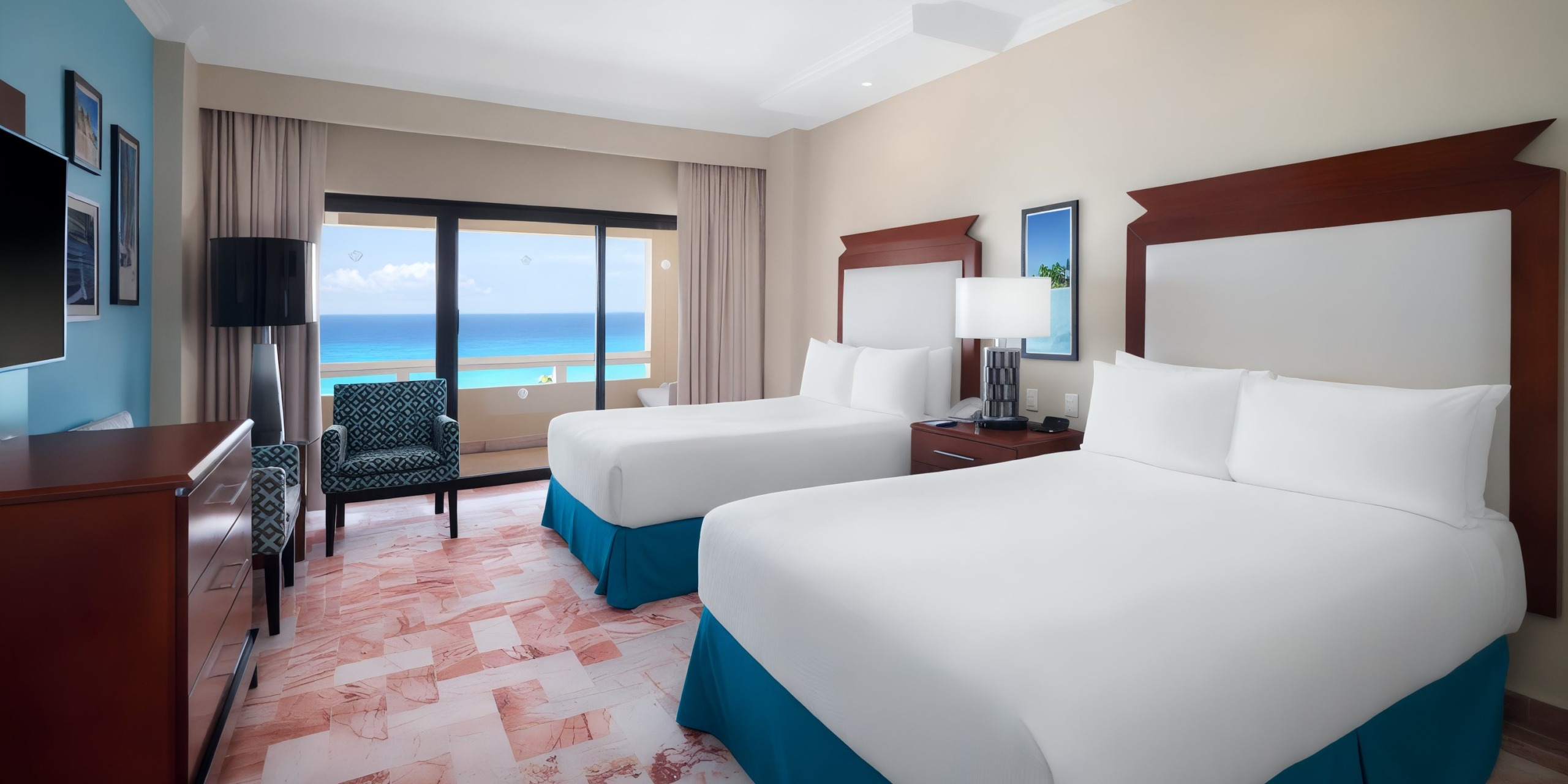 Room at the Wyndham Grand Cancun featuring two double beds, a TV, a dresser, and a window with an ocean view.