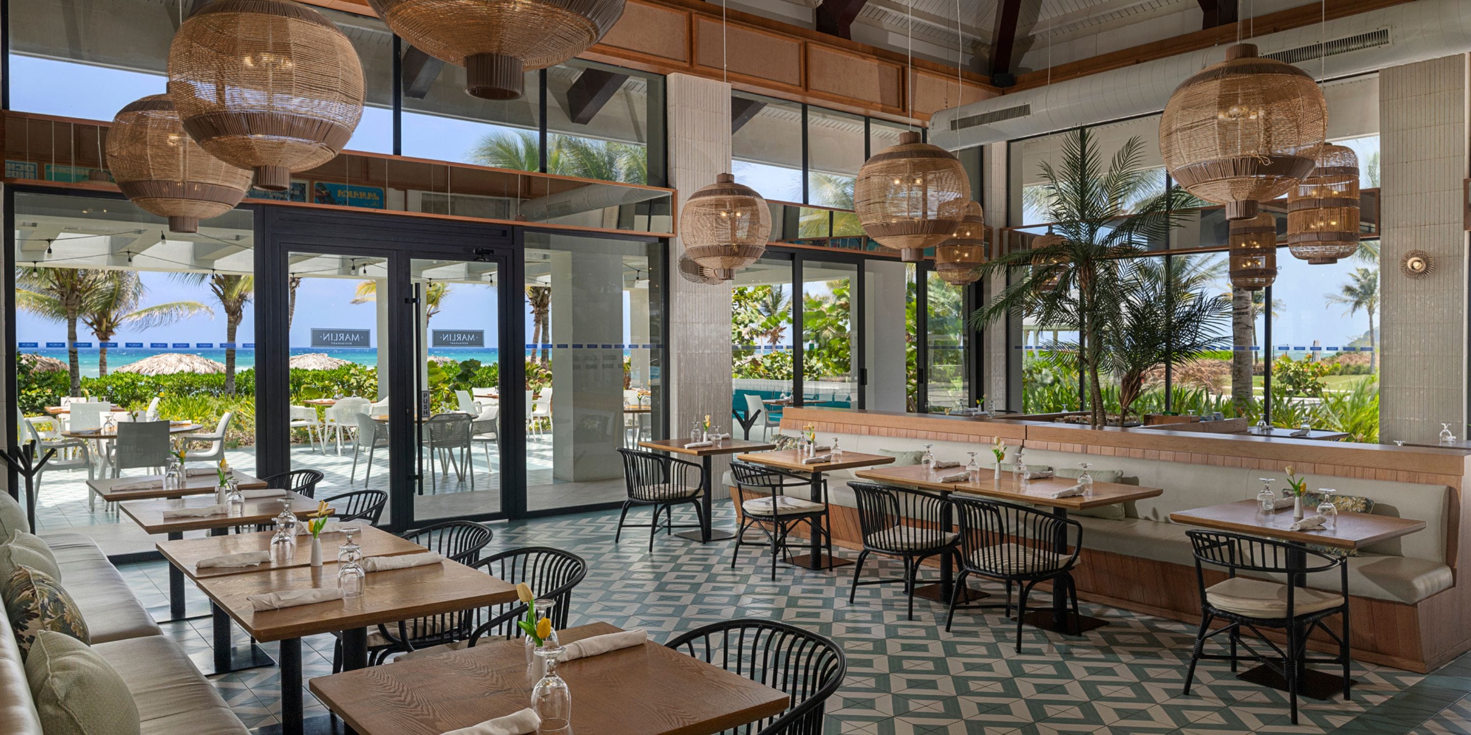 Ocean Eden Bay offers a stunning destination wedding setting with wooden tables, wicker chairs, and palm views.