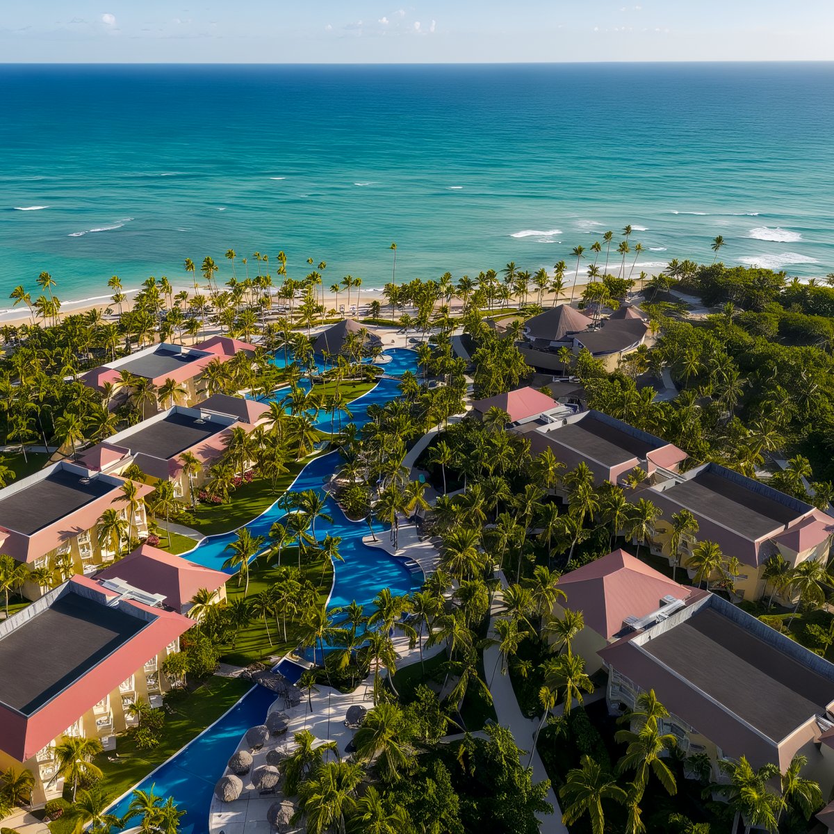 Aerial view of Wyndham Alltra Punta Cana, a beachfront resort featuring multiple pools, palm trees, and buildings by the ocean.