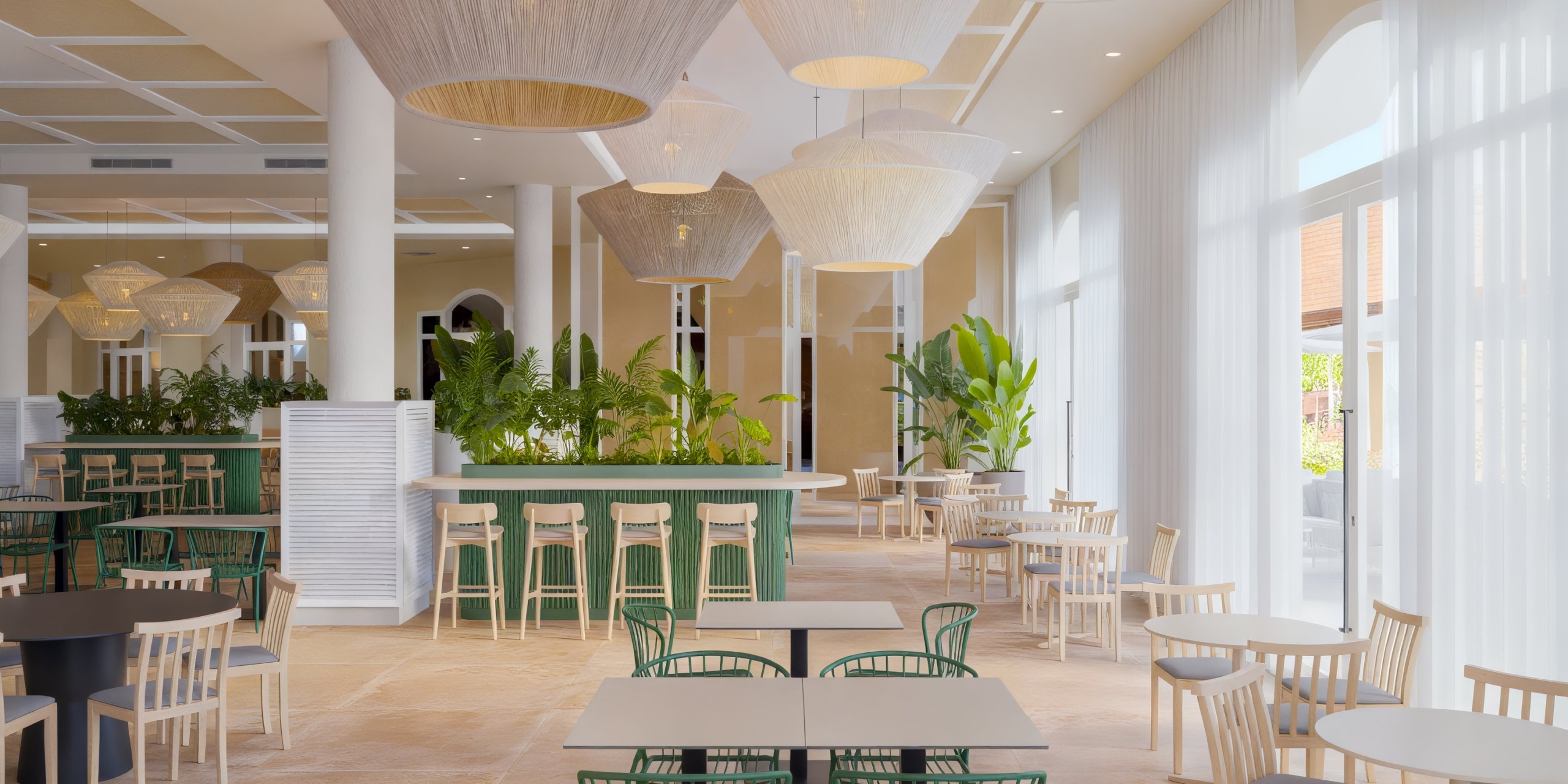 The Wyndham Alltra Punta Cana features a modern, spacious restaurant interior with light wood furniture, green accents, large pendant lights, and tall windows that fill the space with natural light.