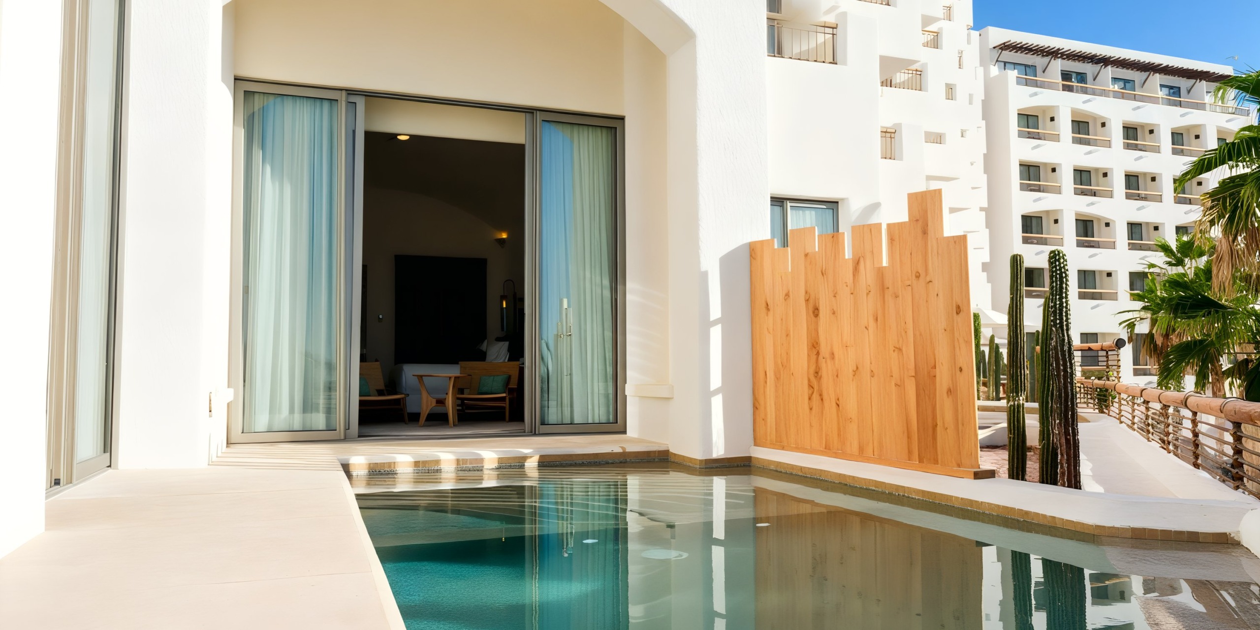 The Marquis Los Cabos offers modern rooms with sliding glass doors that open to a private pool. A wooden partition and nearby palm trees enhance privacy and create a tropical ambiance.