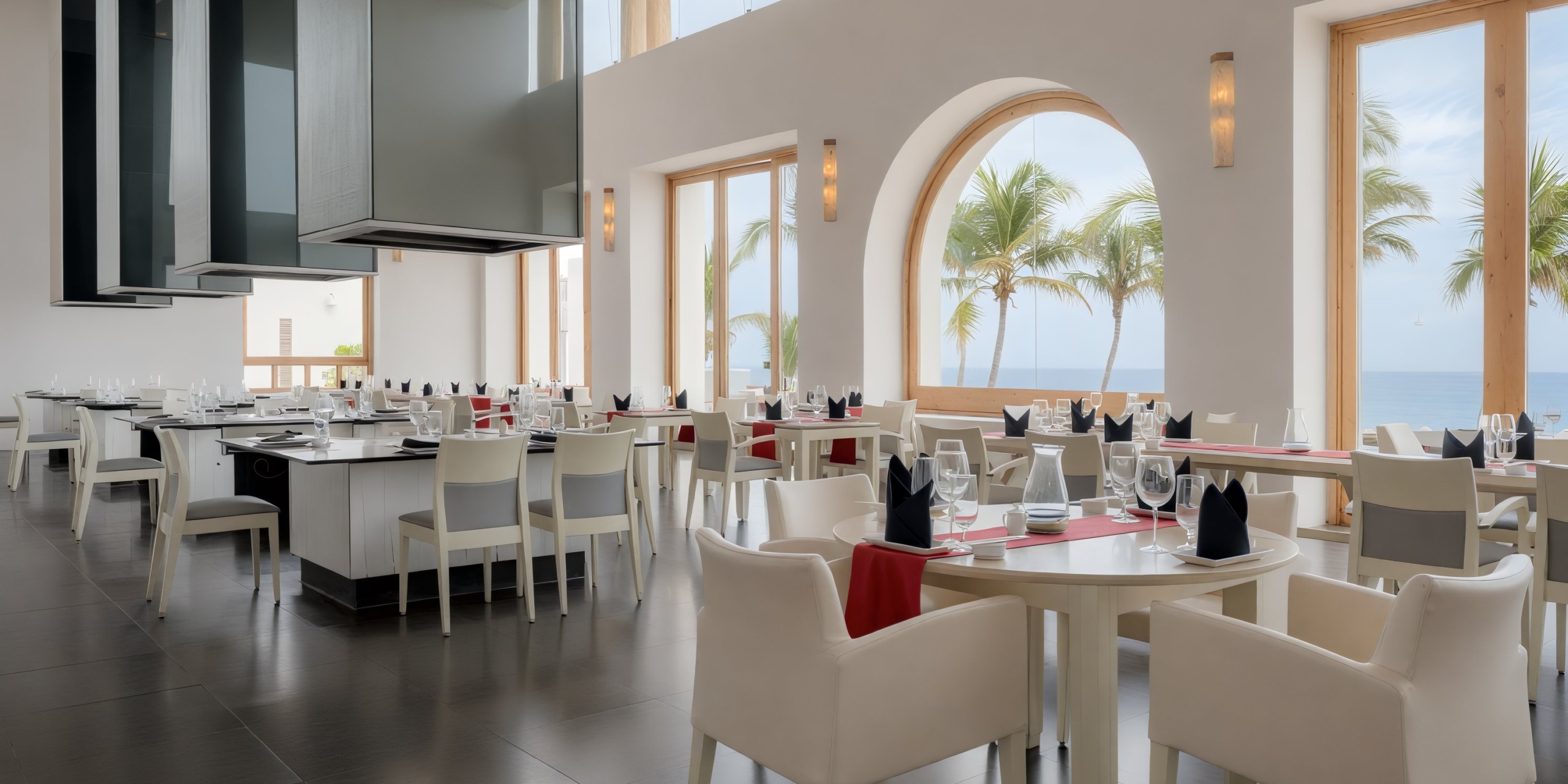 The Marquis Los Cabos features a contemporary, airy restaurant interior with white tables and chairs, neatly set tableware, expansive windows, and a scenic view of palm trees and the ocean.