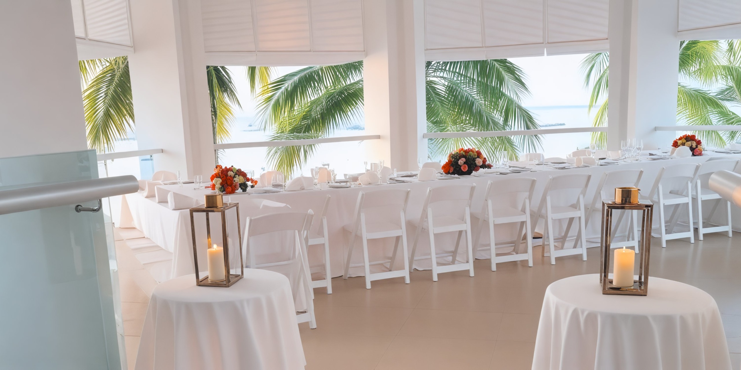 A sophisticated wedding dining arrangement featuring white chairs and floral centerpieces, set against a backdrop of swaying palm trees, perfect for a destination wedding.