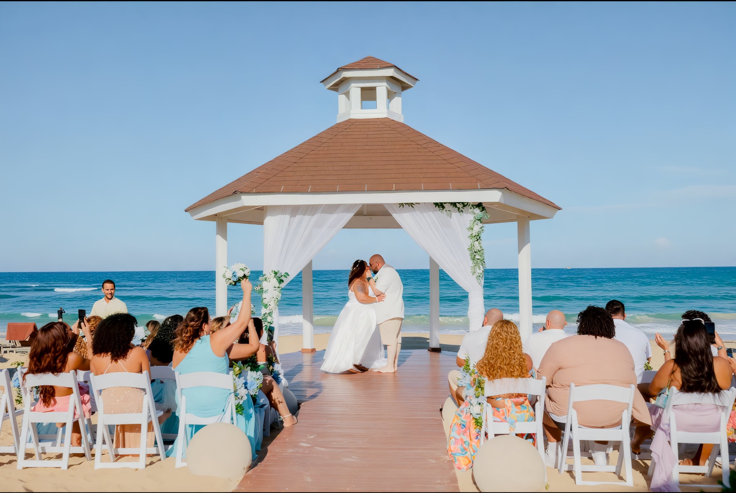 A beautiful destination wedding ceremony took place on the beach, where the couple shared a romantic kiss under a charming gazebo.