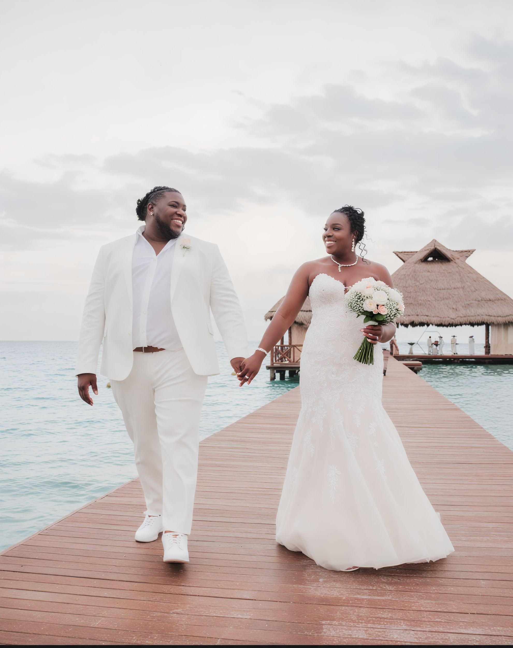 Sheneka and Andre, hand in hand, stood on a wooden pier by the sea, setting the perfect scene for their destination wedding.
