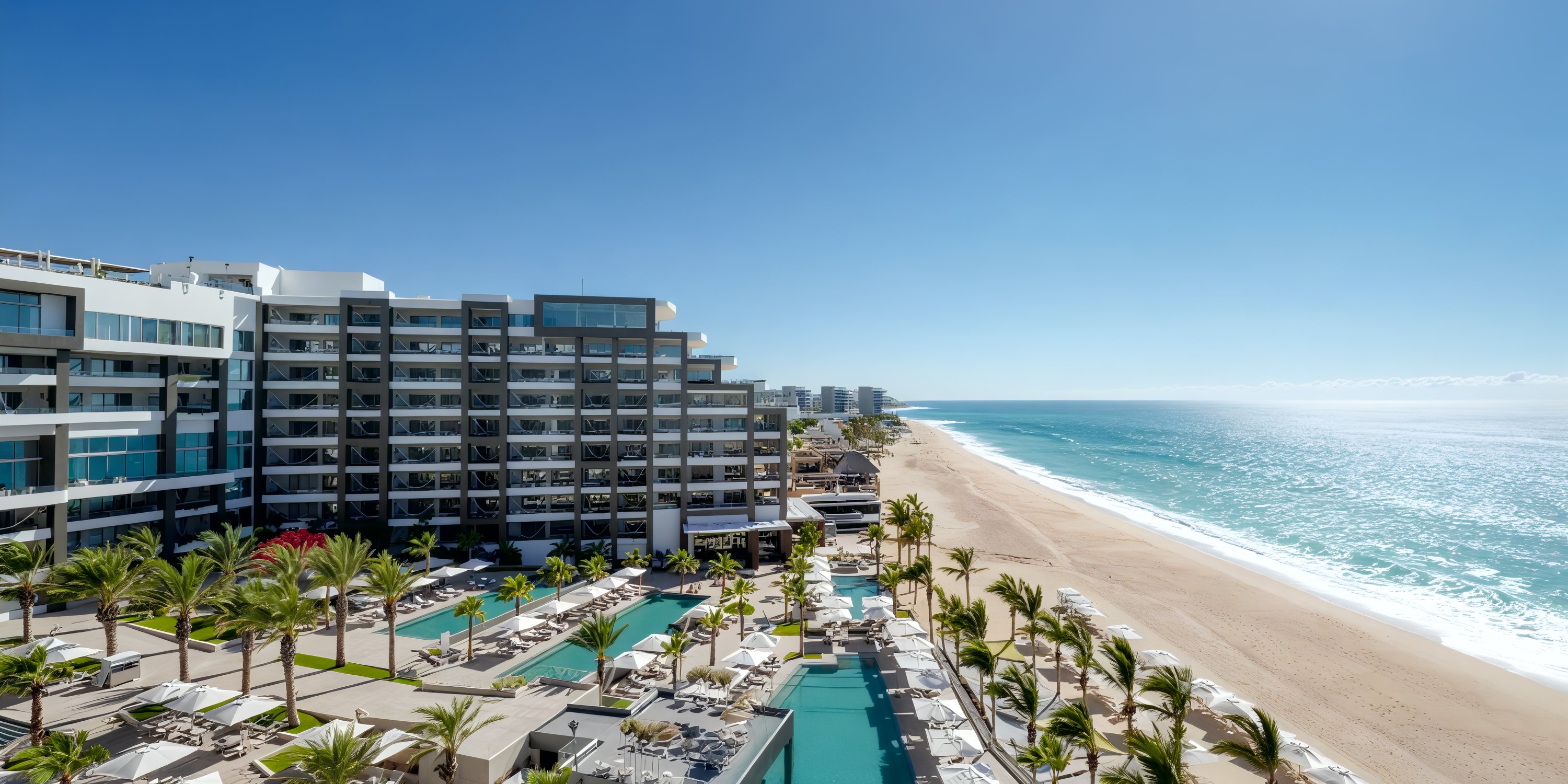Garza Blanca Los Cabos: the perfect destination wedding spot featuring a stunning beach resort with swaying palm trees, luxurious pools, and sleek modern buildings basking in the sunshine.