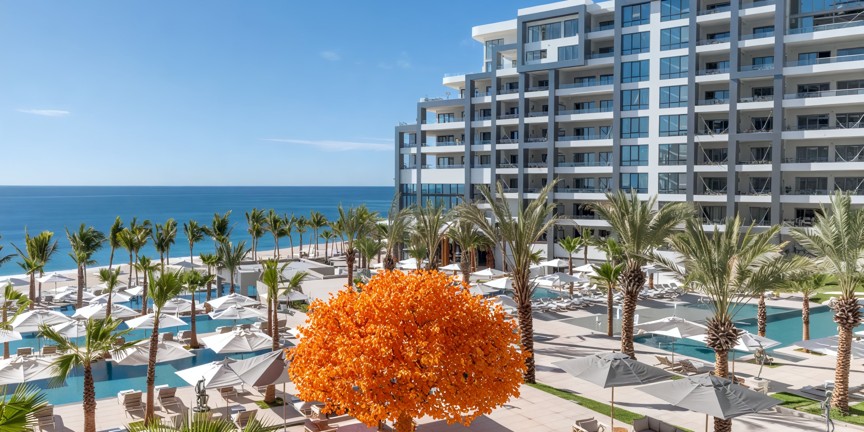 Garza Blanca Los Cabos: a modern beachfront hotel featuring palm trees, a pool, and an orange sculpture, perfect for a destination wedding.