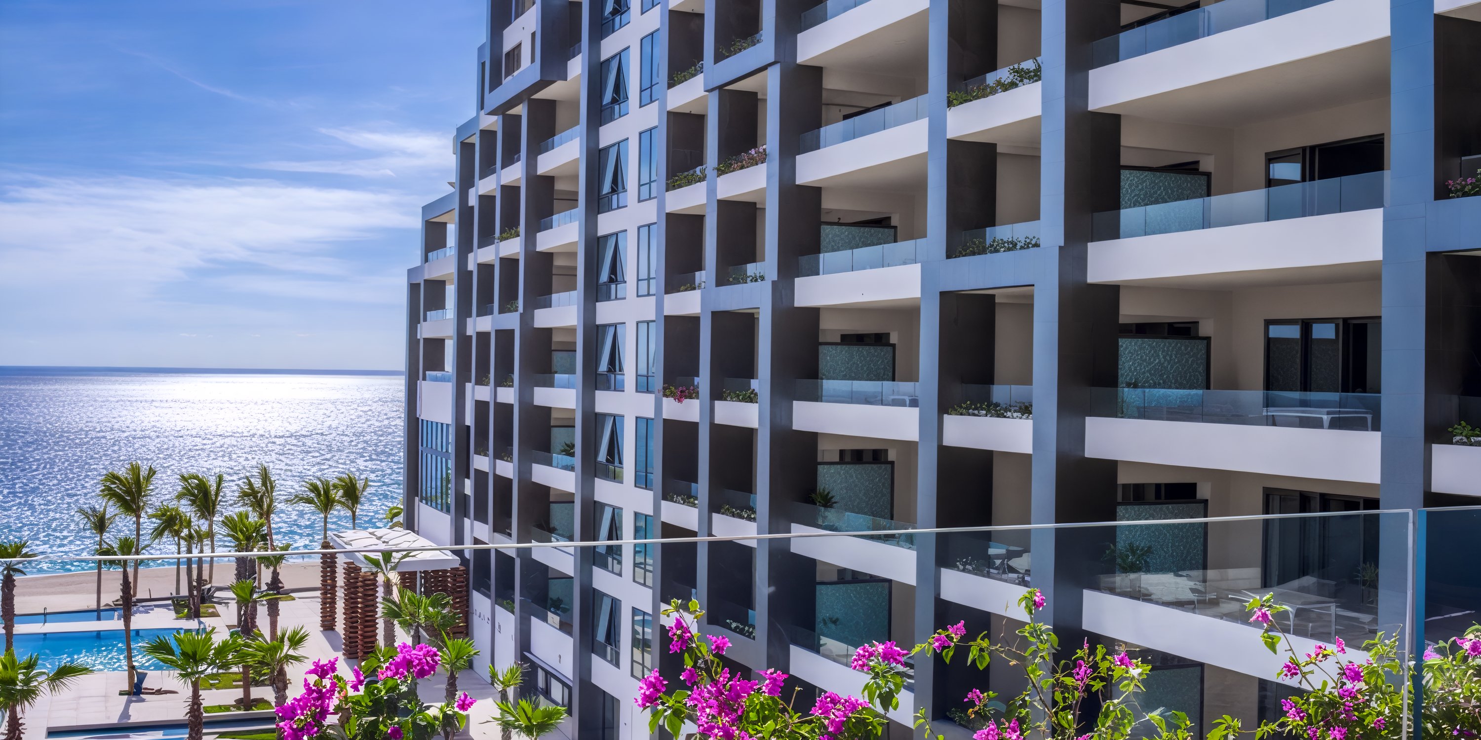 Garza Blanca Los Cabos is a contemporary hotel featuring balconies, stunning ocean views, and vibrant flowers, making it an ideal destination for weddings.