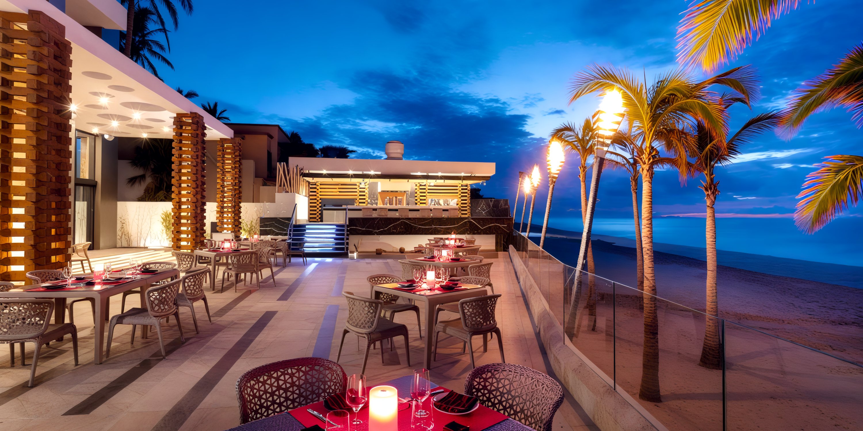Experience the enchanting beachside dining at Garza Blanca Los Cabos, where torches illuminate your evening meal against the breathtaking backdrop of an ocean view at dusk—a perfect setting for a destination wedding.