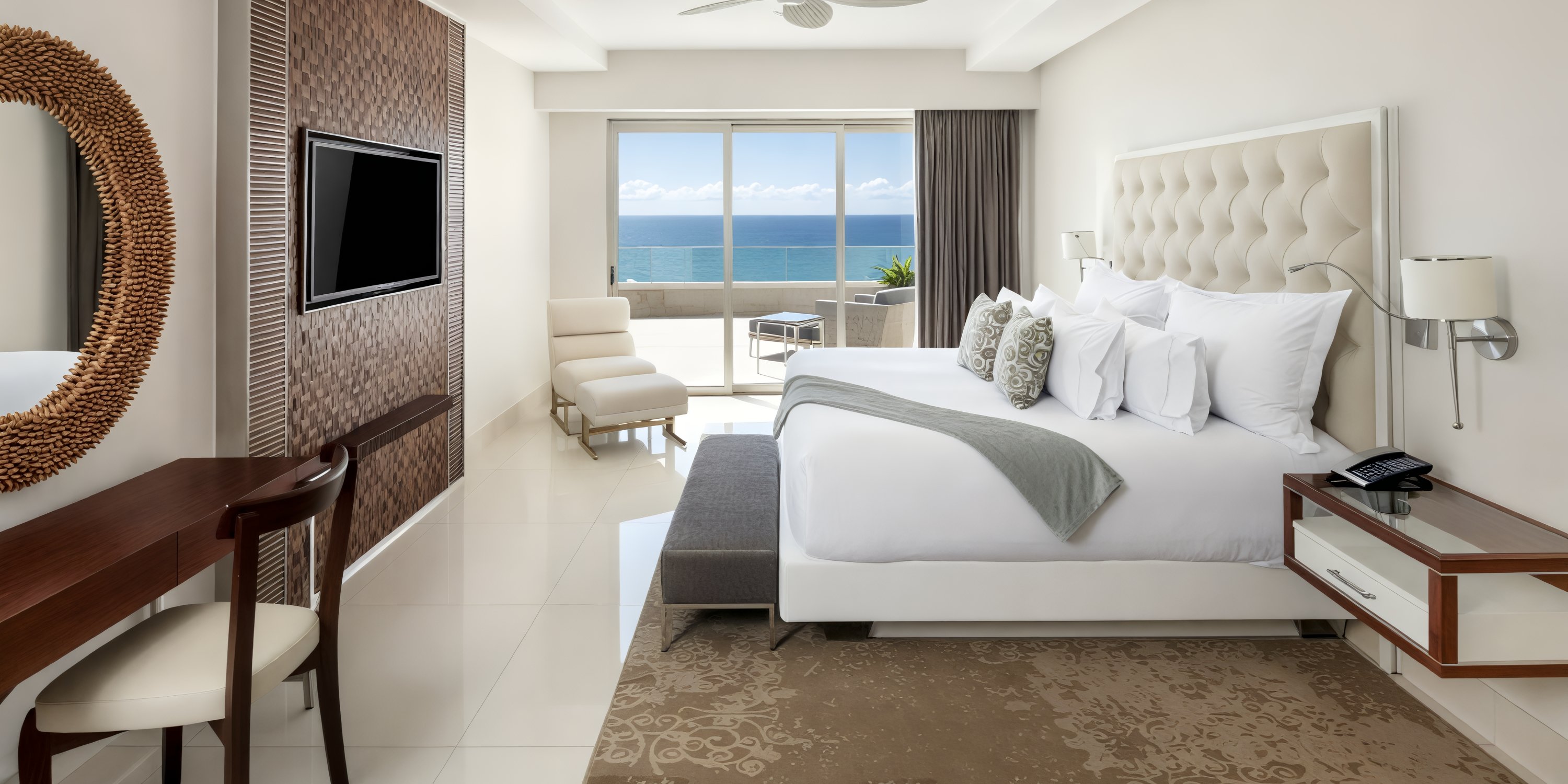 Garza Blanca Los Cabos offers a stunning ocean view room, perfect for your destination wedding. Enjoy amenities such as a large bed, TV, desk, and chair for the ultimate comfort during your special celebration.