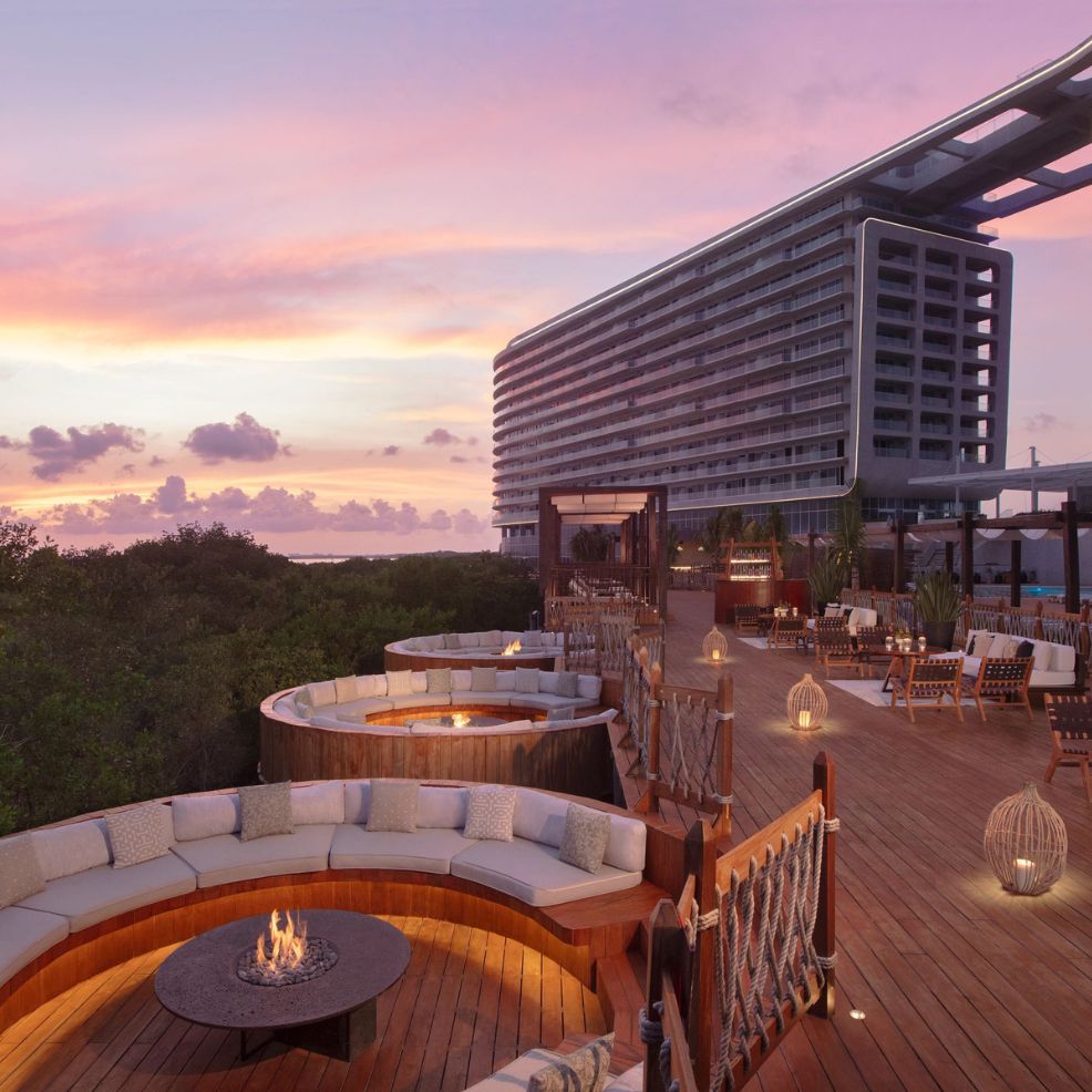 A rooftop terrace featuring circular seating and a fire pit offers the perfect setting for a destination wedding, complete with breathtaking sunset views.