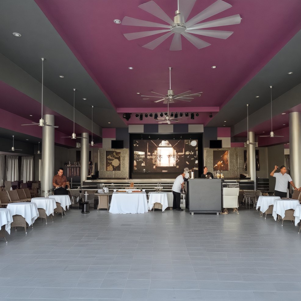 A spacious indoor dining area with elegantly set tables, bustling with people diligently preparing the space for a beautiful destination wedding.