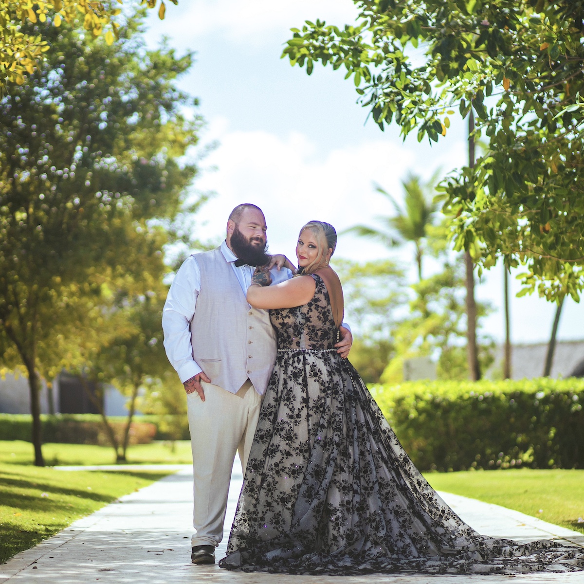 Sheneka and Andre strike a pose in their wedding attire along a sunlit garden path, capturing the essence of their beautiful destination wedding.