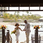 A couple strolls along the beach beneath a wooden arch, creating a romantic setting ideal for a destination wedding.