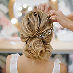 A woman's hair styled in an elegant updo with a decorative hairpiece, perfect for a destination wedding.