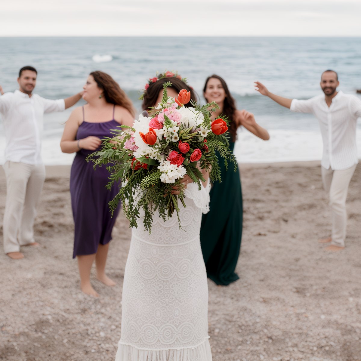 At a stunning Caribbean destination wedding on the beach, the bride tosses her bouquet into a joyful crowd of eagerly reaching guests.