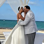 Jamie and Gary share a kiss beneath a white canopy during their beautiful destination wedding by the beach.