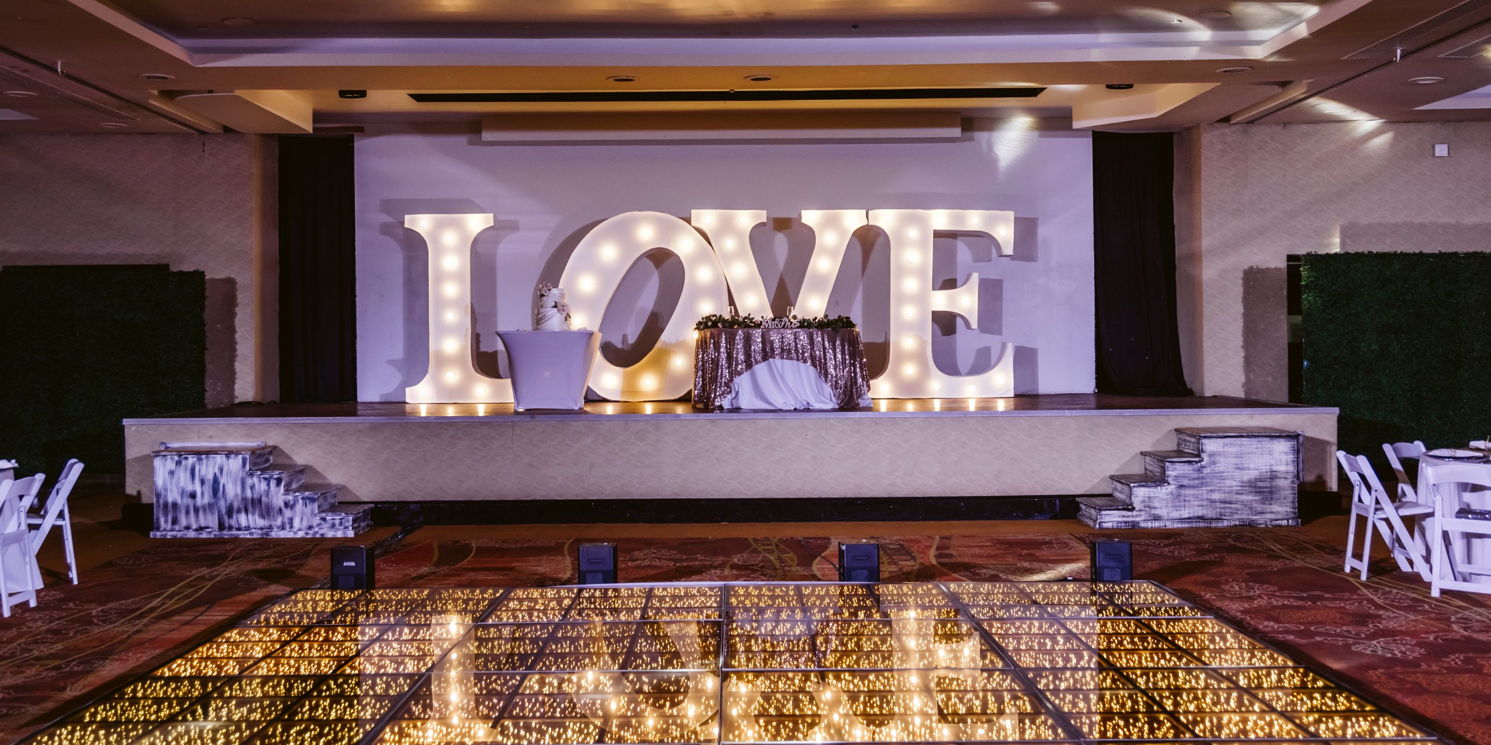 Large "LOVE" letters on stage at a destination wedding at Moon Palace Nizuc, with a shiny dance floor.