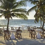 Ideal for destination weddings, with chairs and cocktail tables arranged on a sandy beach.