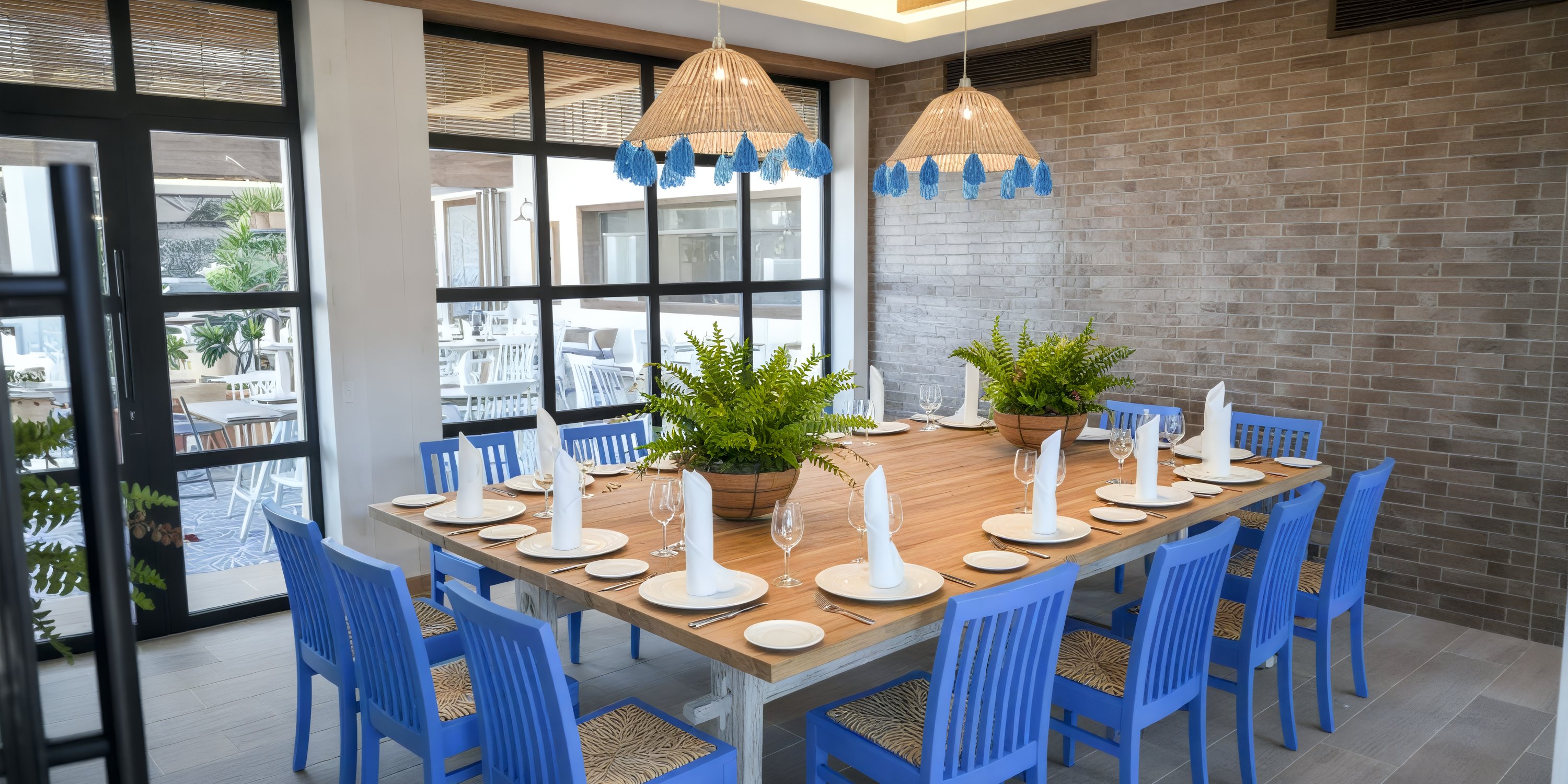 Wedding table for 12 at Bahia Principe Grand El Portillo with blue chairs and potted plant centerpieces.