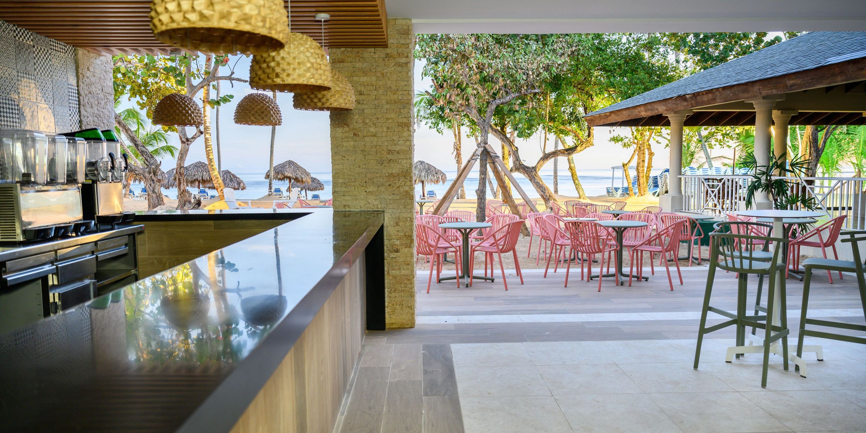 Outdoor beachside bar at Bahia Principe Grand El Portillo, ideal for destination weddings, with pink chairs.