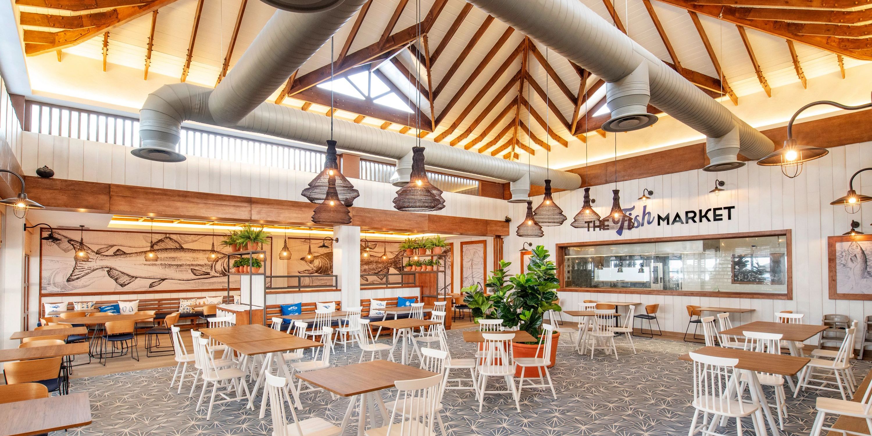 Bright, spacious destination wedding venue at Bahia Principe Grand El Portillo with wood tables, white chairs, and exposed beams.