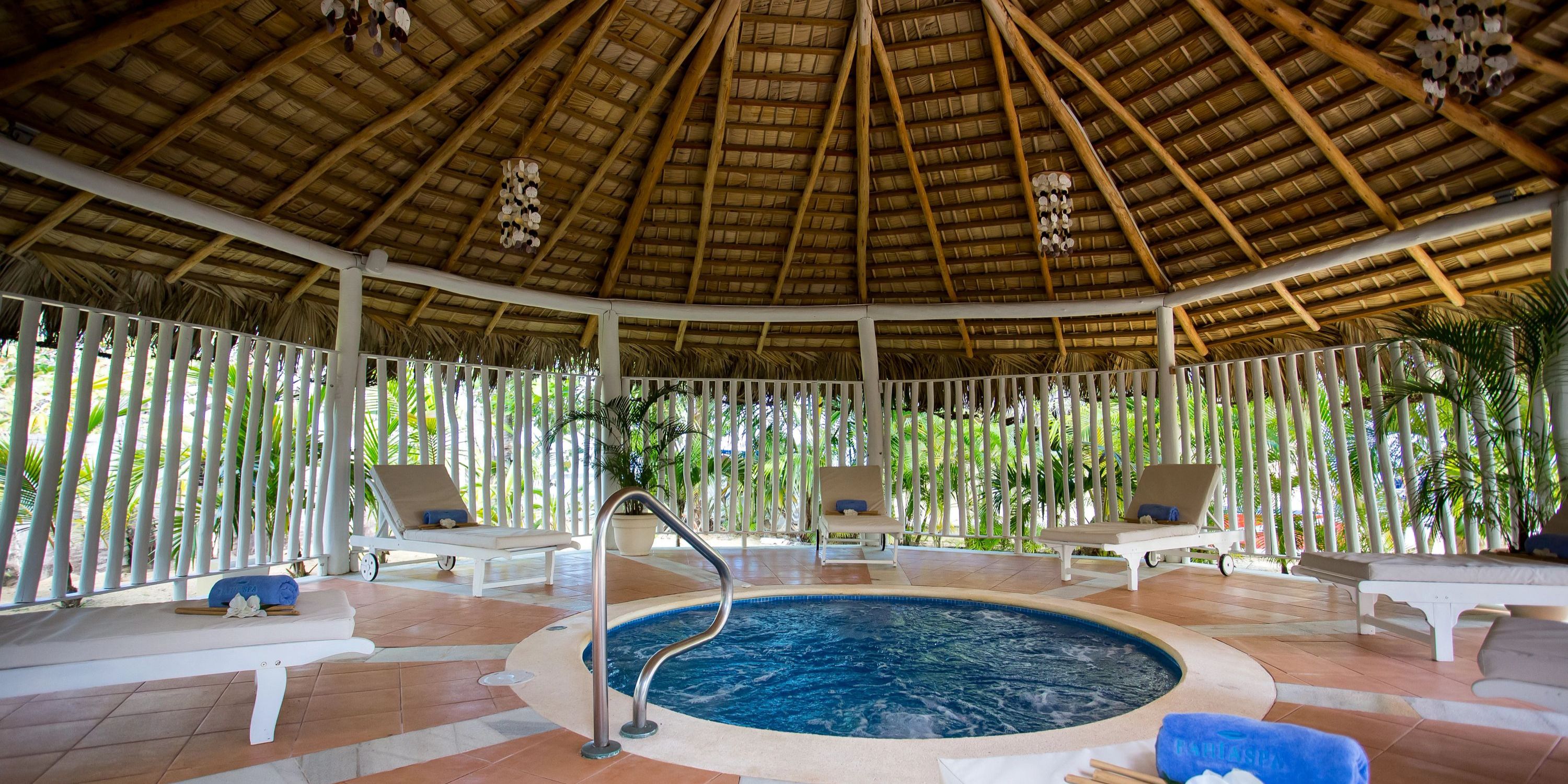 Indoor hot tub with loungers and plants, perfect for a relaxing destination wedding at Bahia Principe.