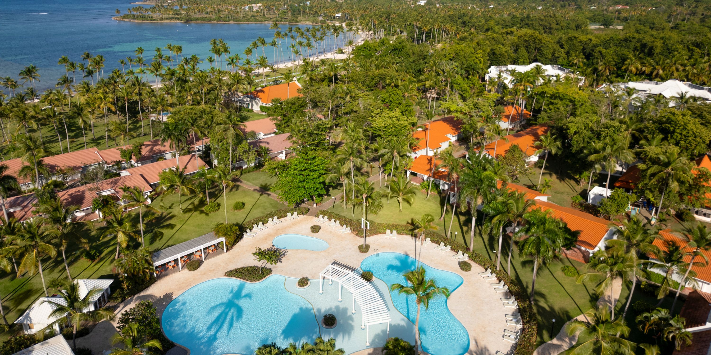 Aerial view of Wyndham Alltra Punta Cana, an ideal destination wedding spot with pools, palms, and coast.