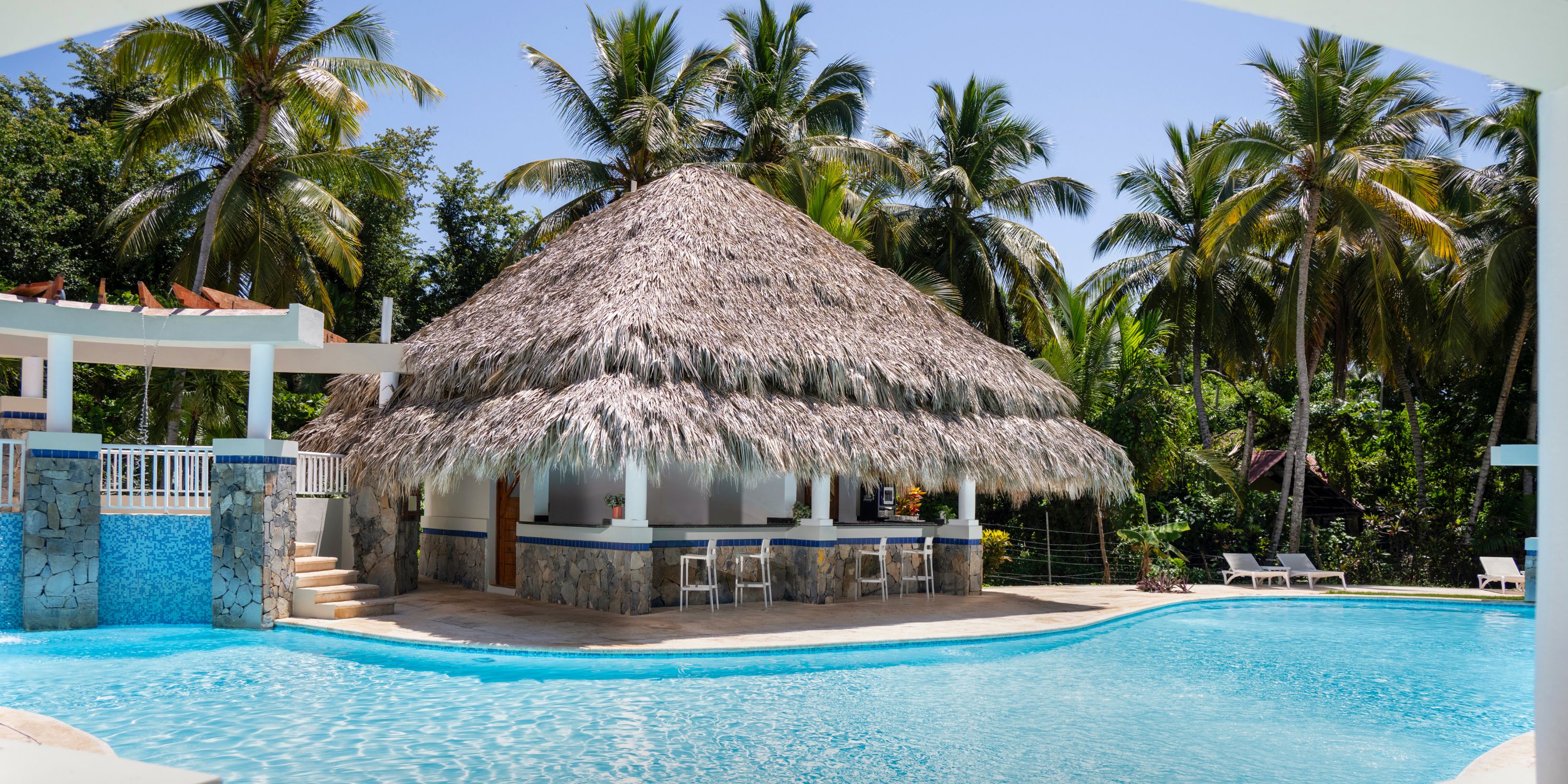 Wyndham Alltra Punta Cana: Ideal destination wedding spot with thatched-roof pool bar, palms, lounges.
