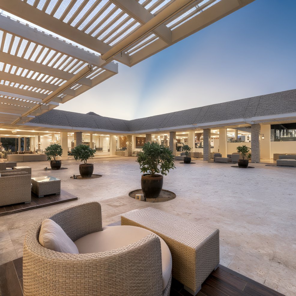 Elegant outdoor lounge with wicker seating and potted plants, perfect for a destination wedding at sunset.