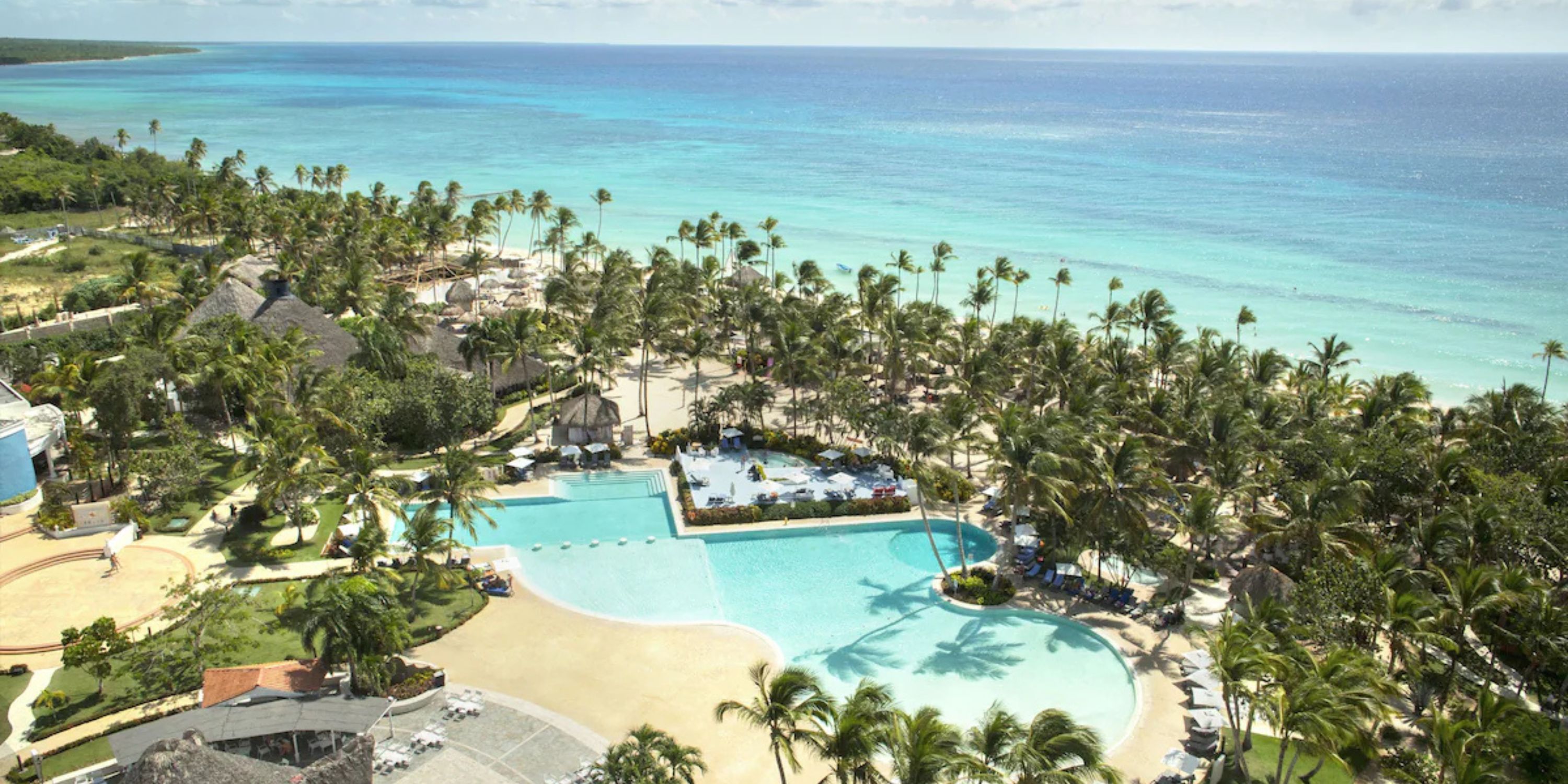 Aerial view of Catalonia Bayahibe, a beachfront resort with pools and palm trees—ideal for weddings.