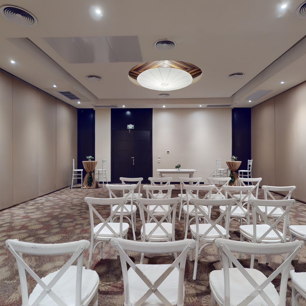 Small conference room, white chairs arranged as for a destination wedding, neutral walls and carpet.