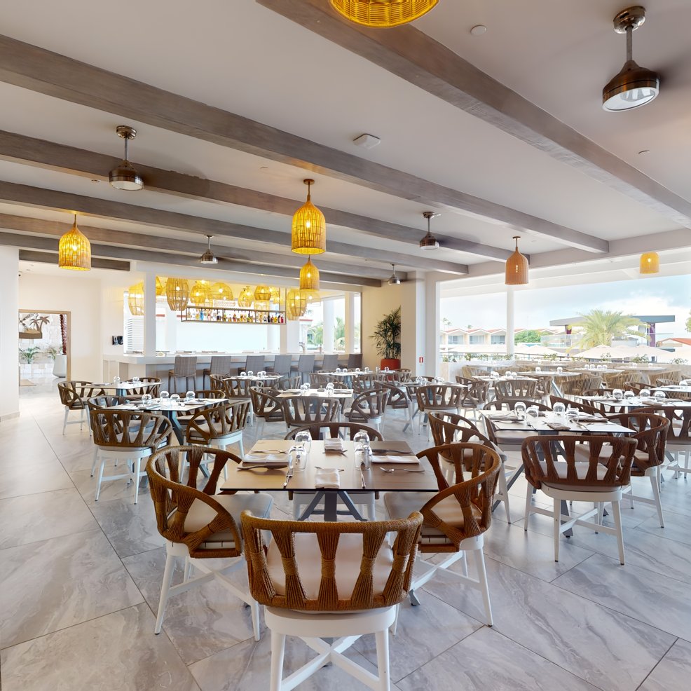 Chic restaurant dining space with wooden chairs, set tables—ideal for a stylish destination wedding.
