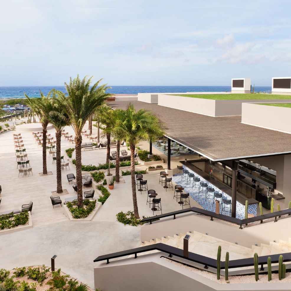 Elegant outdoor bar and seating area with palm trees—perfect for a destination wedding by the ocean.