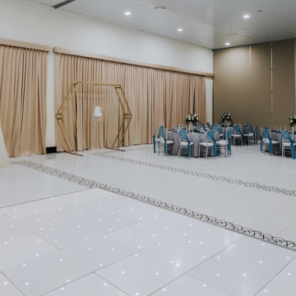 Elegant wedding event hall with draped curtains, adorned tables, and a striking geometric arch.