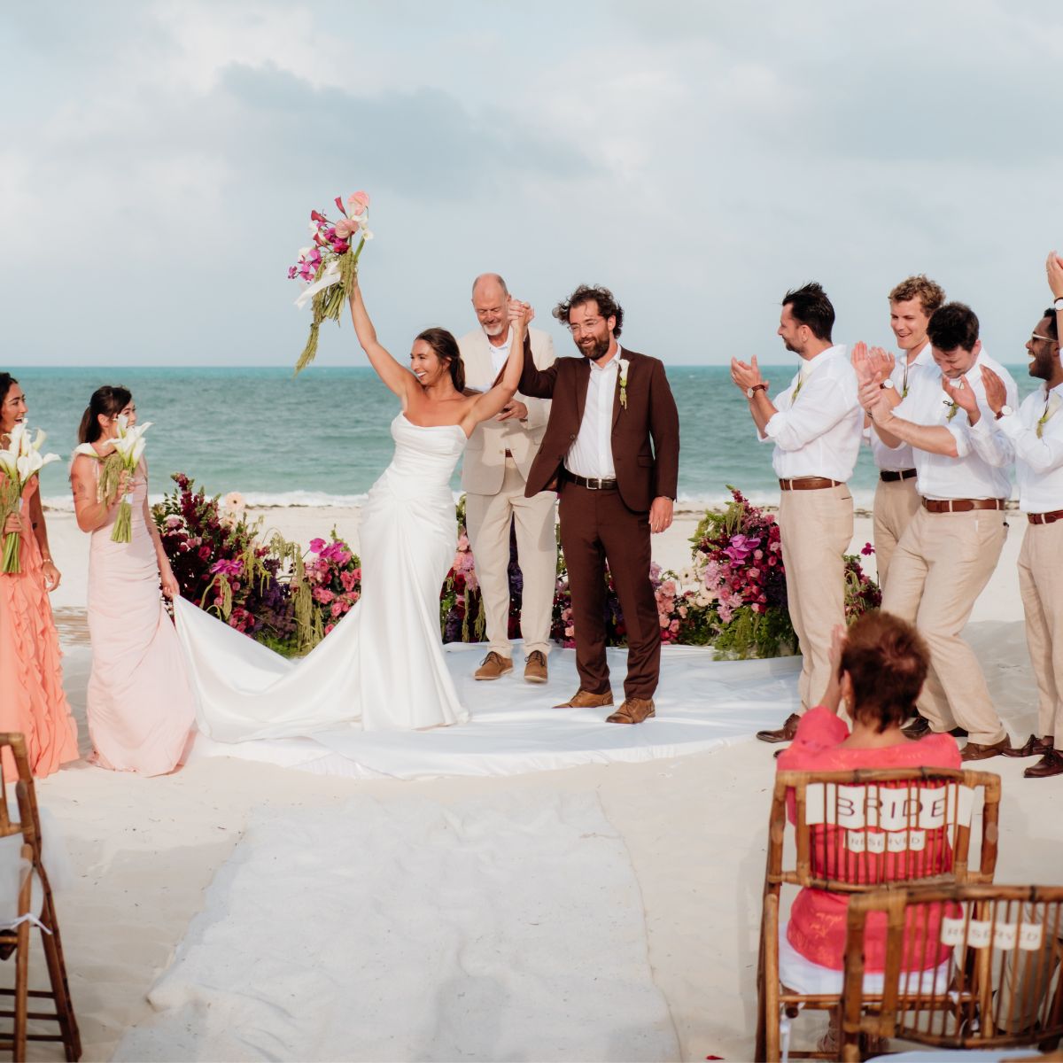 Ethan and Erica celebrate their destination wedding on the beach as guests applaud during the ceremony.