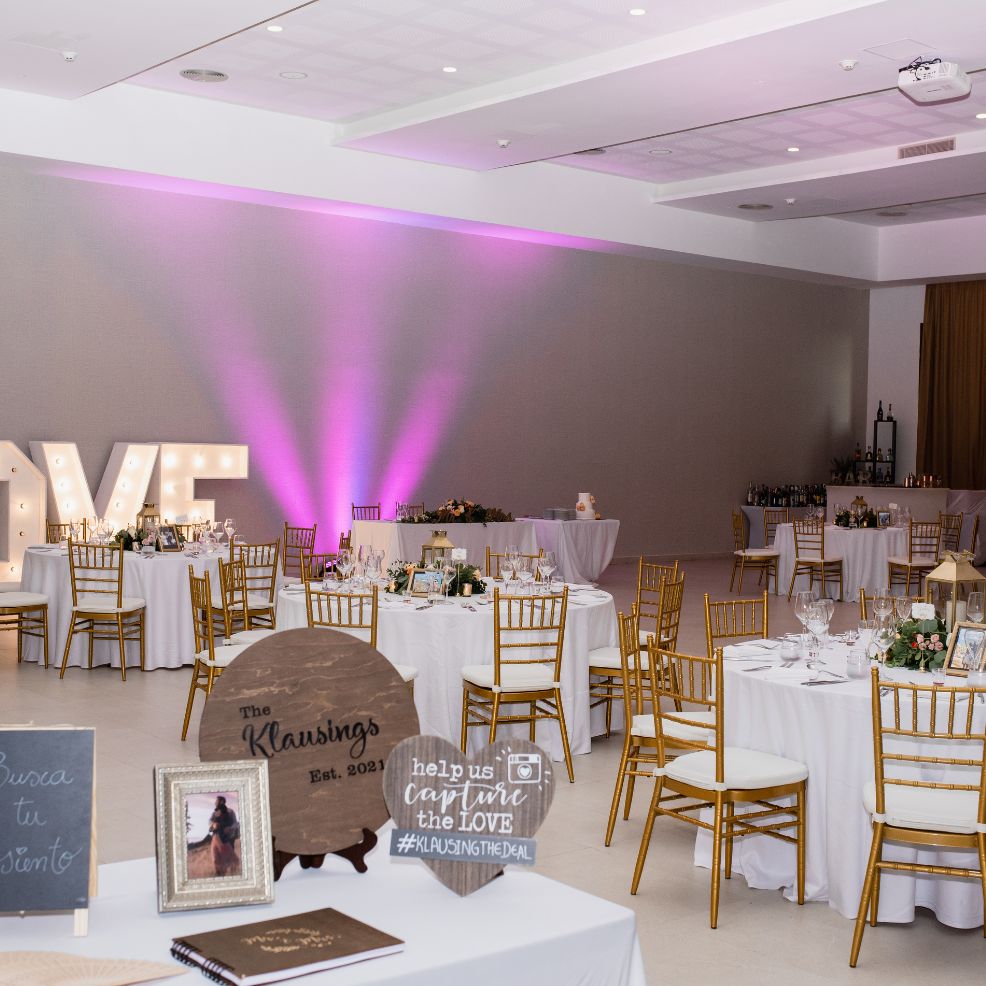 Elegant destination wedding reception hall featuring gold chairs, decorated tables, and glowing LOVE letters.