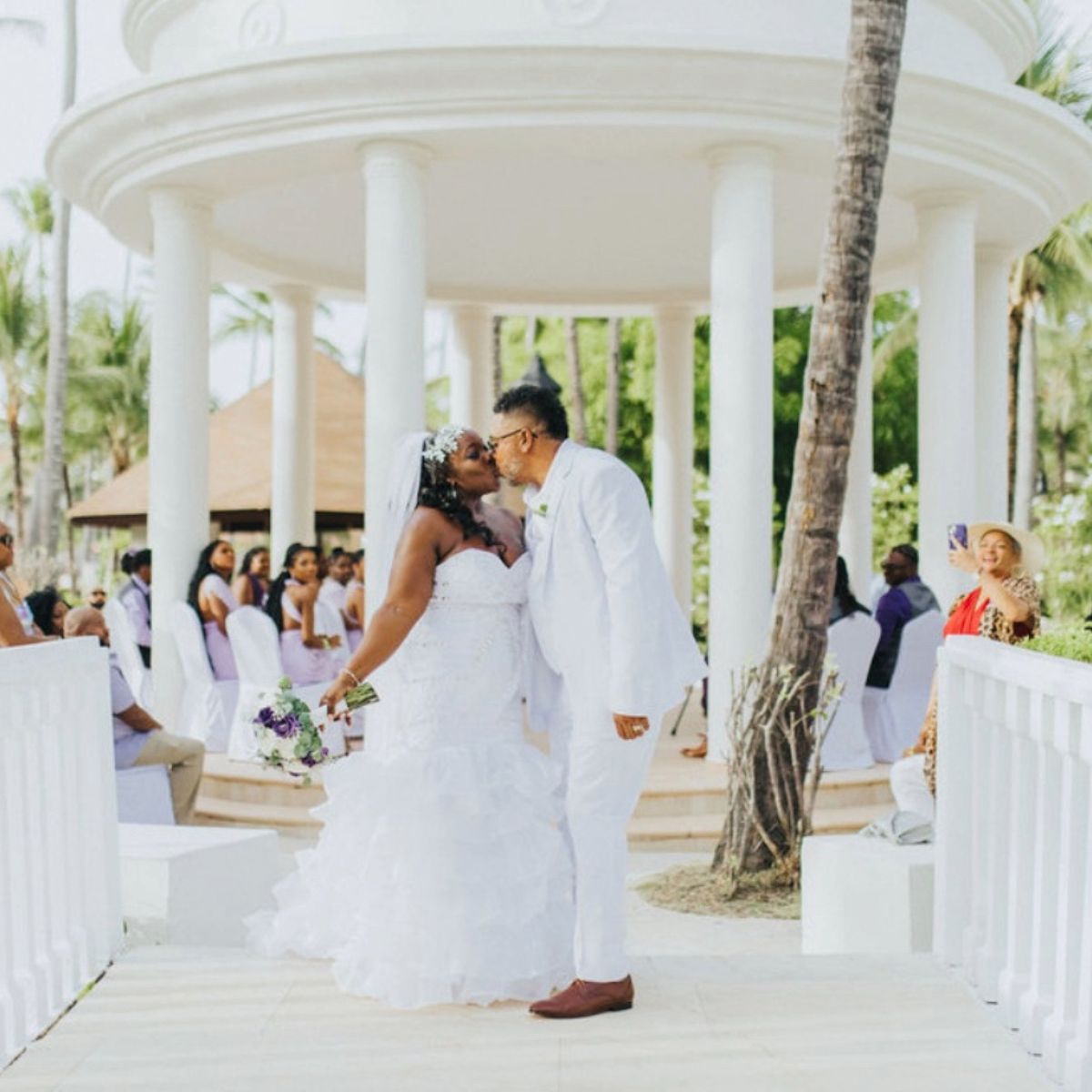 Ethan and Erica (Copy) share a kiss at their destination wedding ceremony in front of guests.