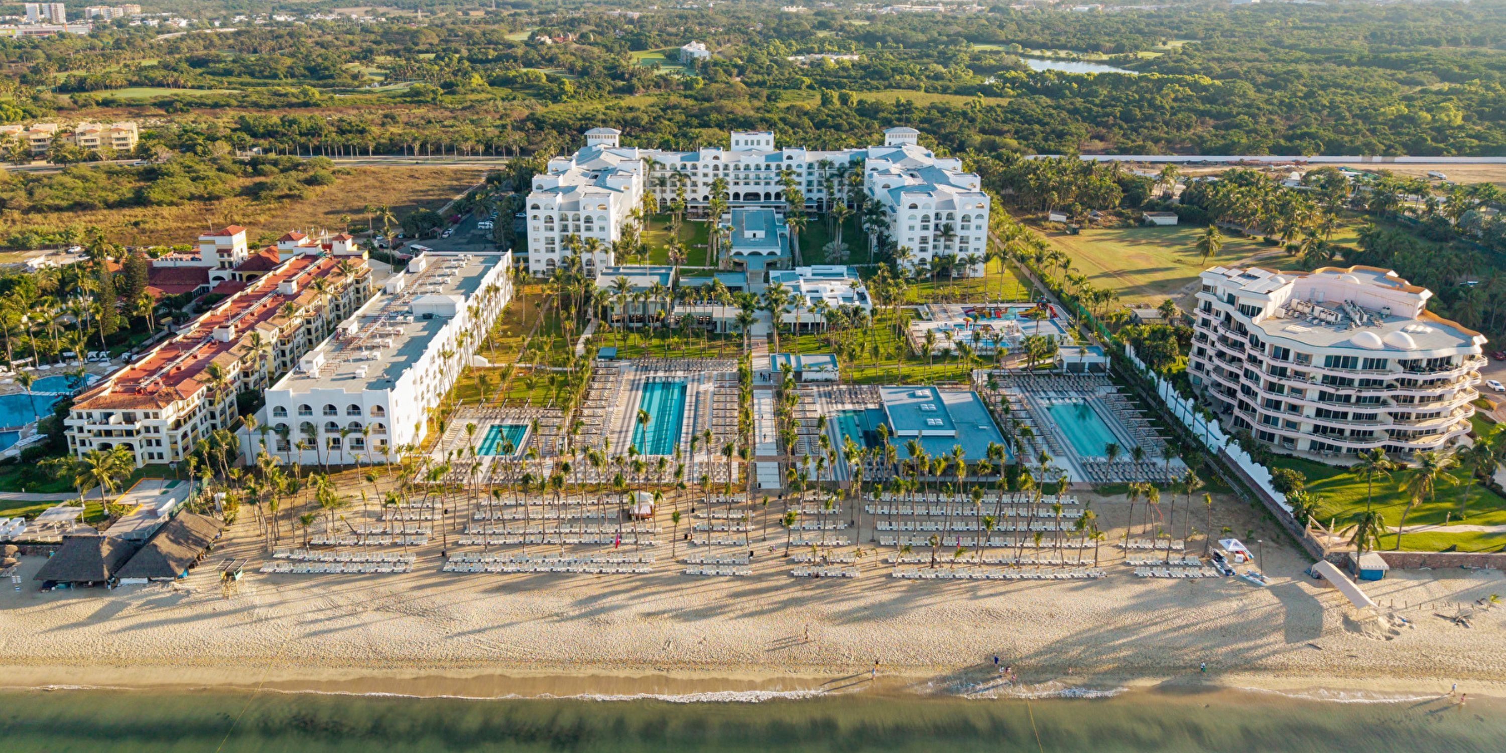 Aerial view of Hotel Riu Jalisco, an ideal destination wedding spot with pools and palm trees by the ocean.