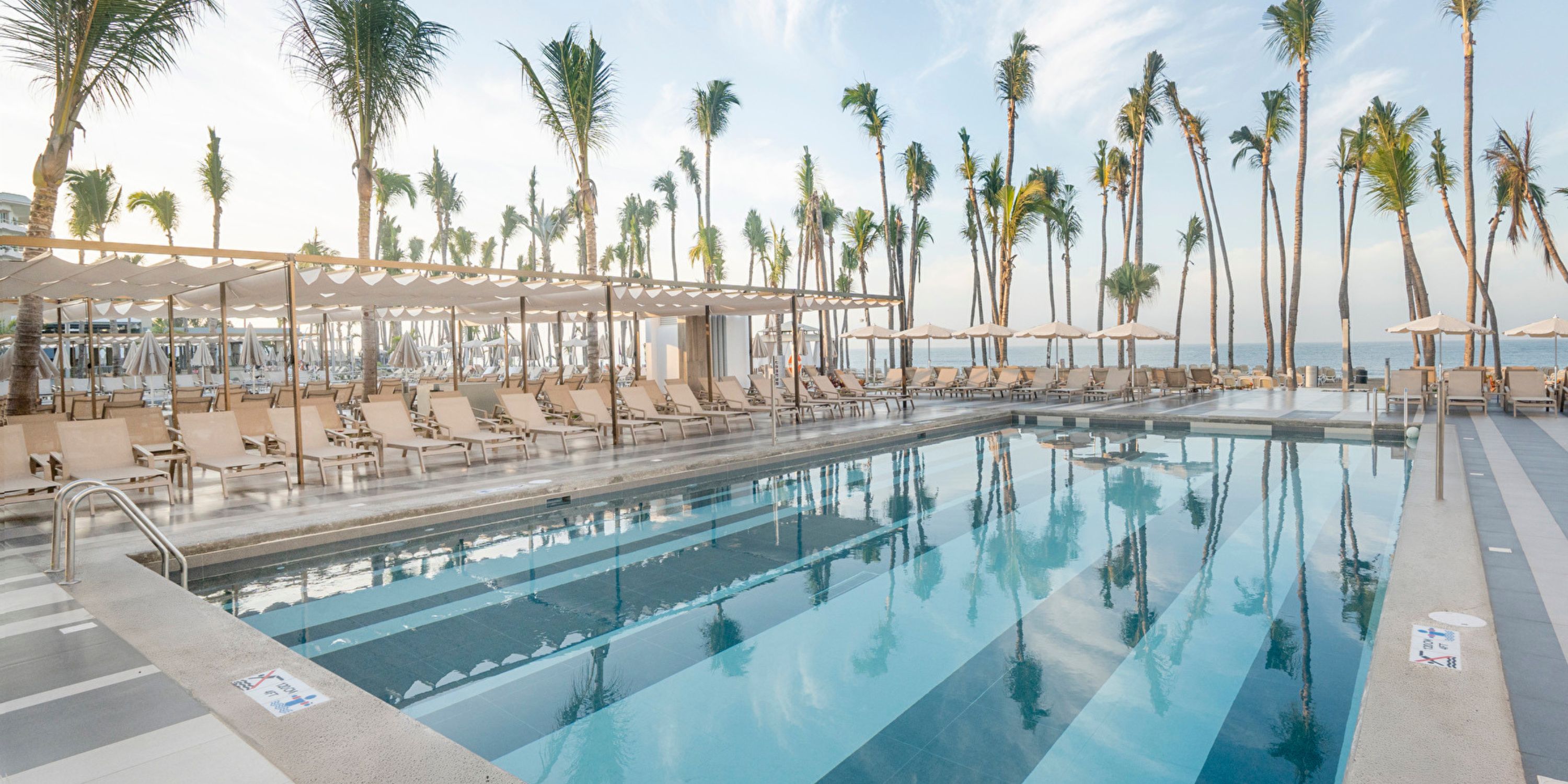 Hotel Riu Jalisco: outdoor pool with lounge chairs, palm trees, ocean views—ideal for weddings.