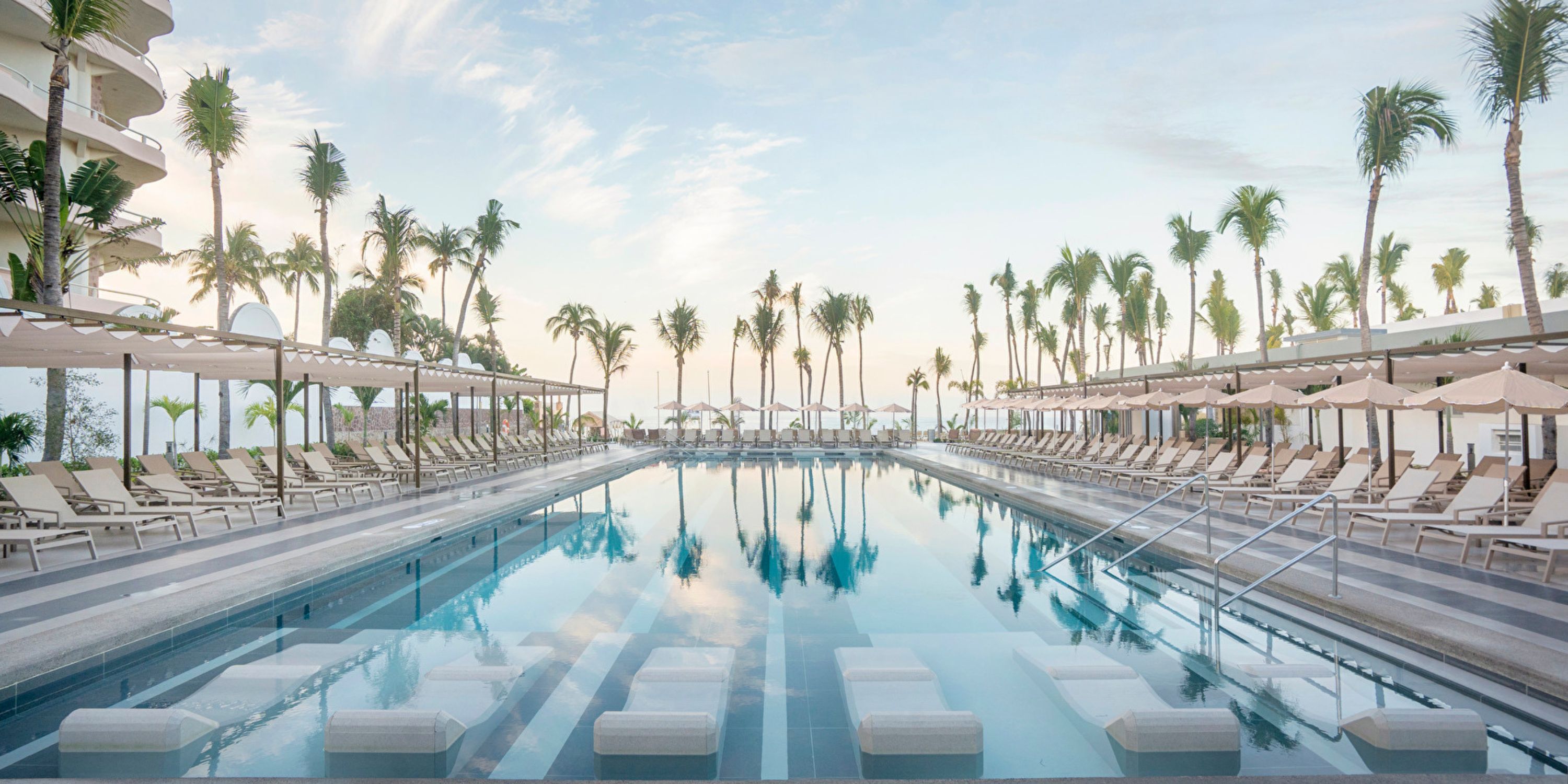 Hotel Riu Jalisco’s outdoor pool with lounge chairs and palm trees is perfect for a destination wedding.